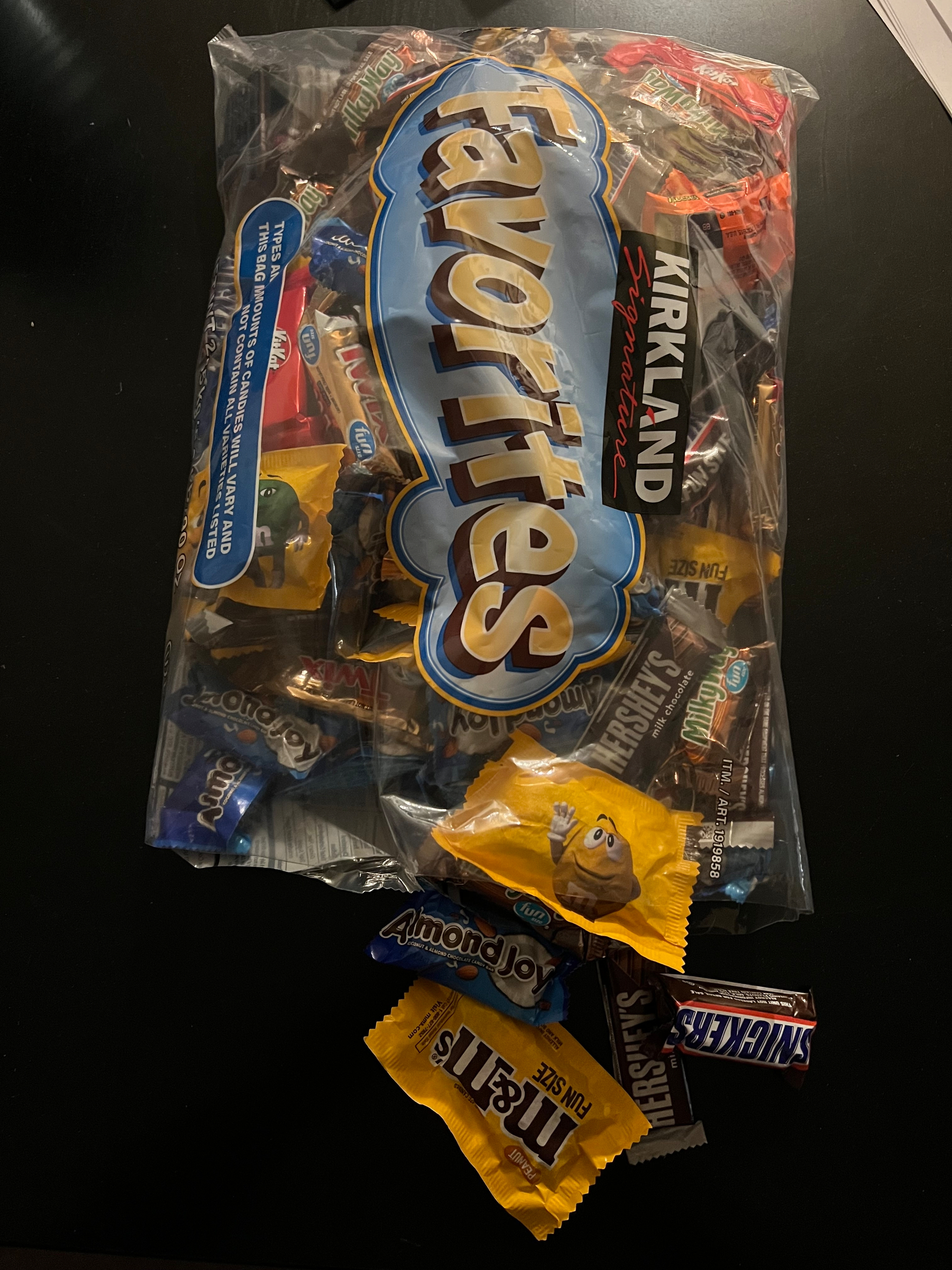 A bag of Kirkland Signature Favorites candy with assorted chocolates spilling out, including Snickers, Almond Joy, and Reese's.