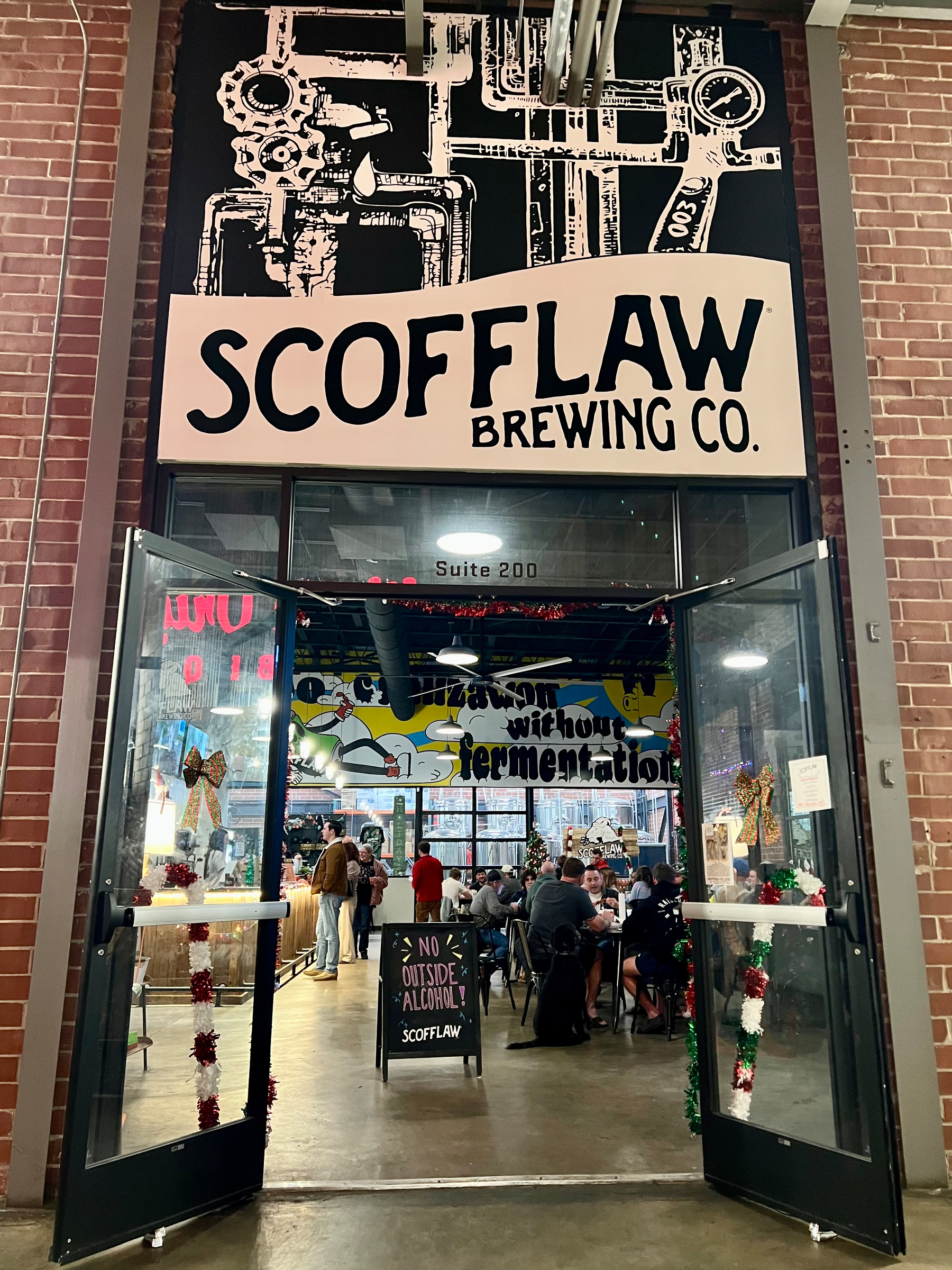 A brewery entrance with a sign reading Scofflaw Brewing Co. and people gathered inside.