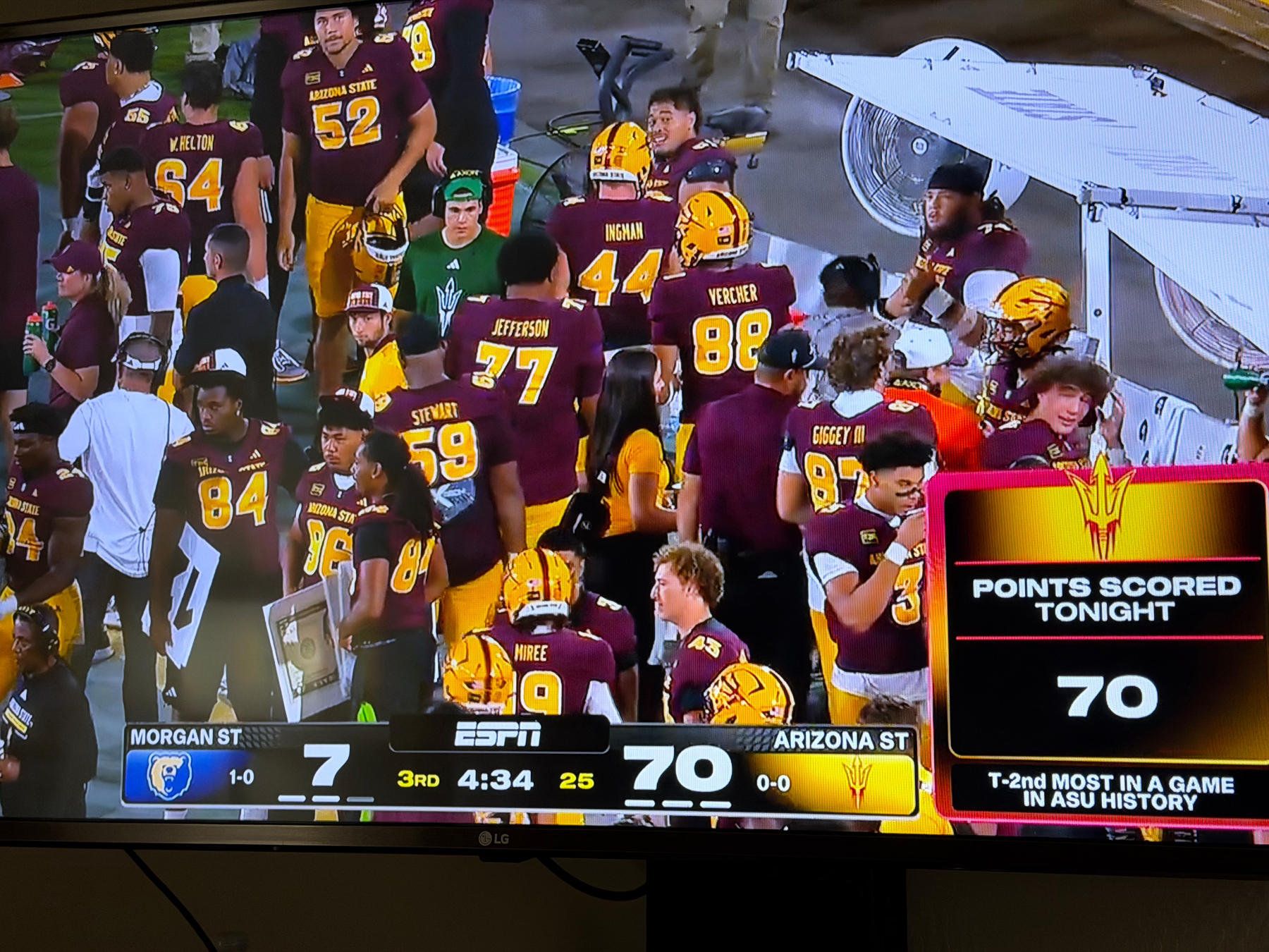 Arizona State football players and staff are gathered on the sidelines during a game against Morgan State, with the scoreboard showing Arizona State leading 70 to 7 in the third quarter.