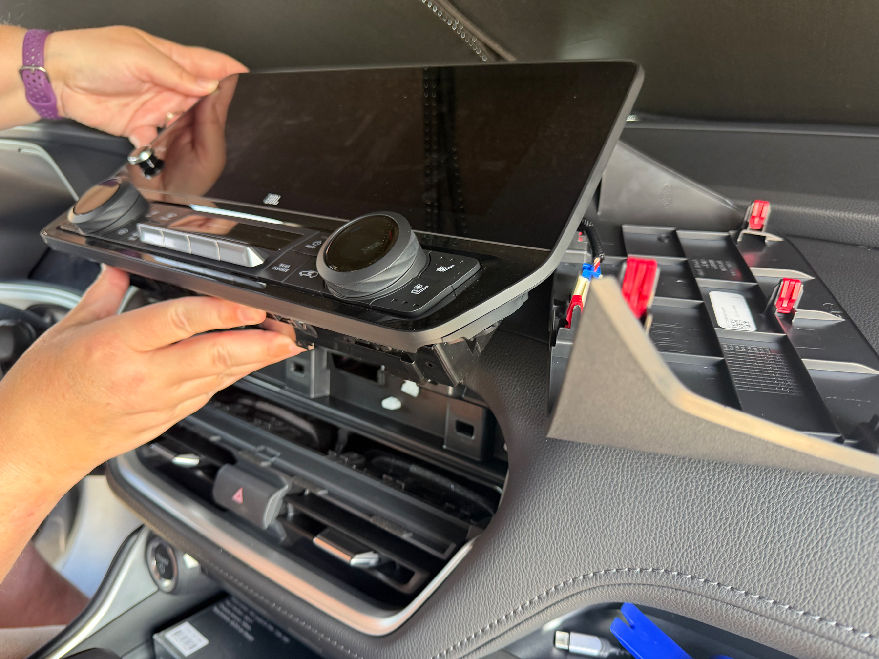 A person is installing or removing a car's dashboard display and control panel.