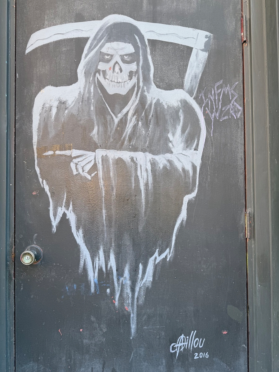 a shadowy figure of the Grim Reaper painted on a dark coloured door