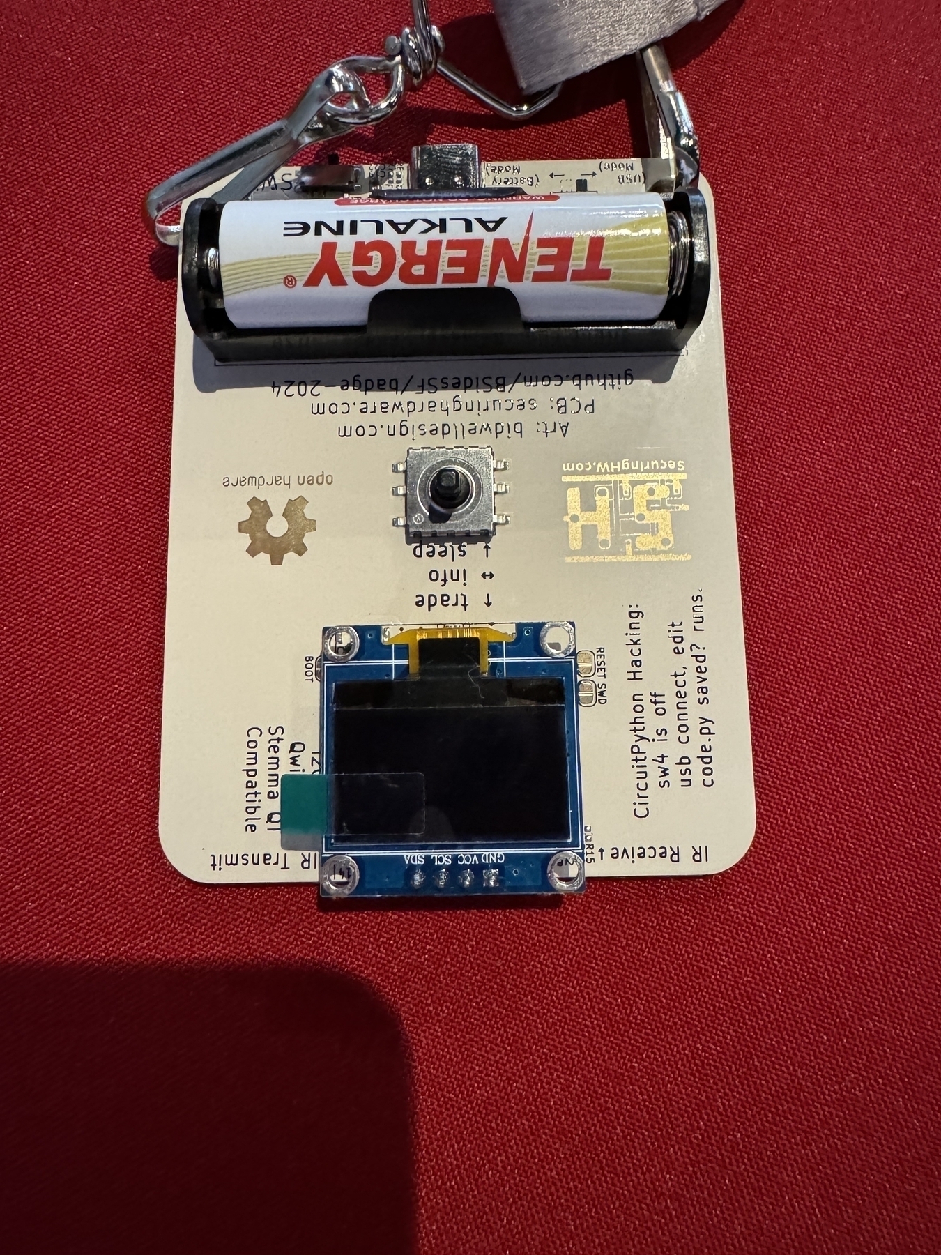 The back of the badge showing the electronics, a tiny display, and how to program it with Python.