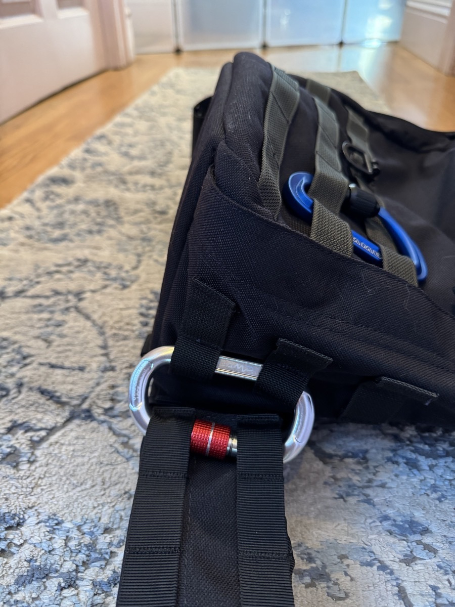 IMG_2461.jpeg Close-up view of the carabiner passed through 2 loops on the belt and 2 loops of the bag so that they're locked together.