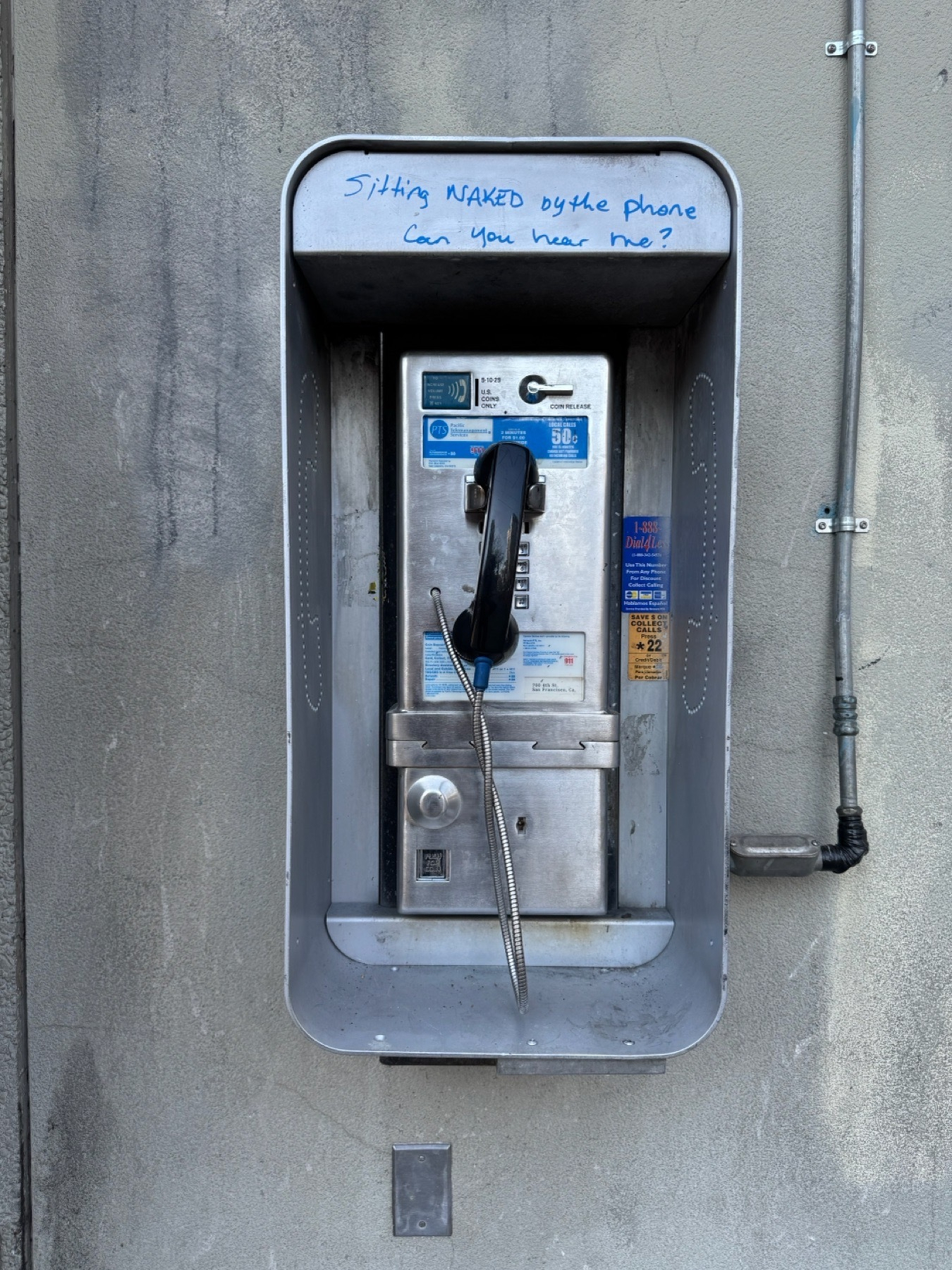Photo of a payphone. Someone has written on its box with a blue marker: &ldquo;sitting naked by the phone, can you hear me?&rdquo;