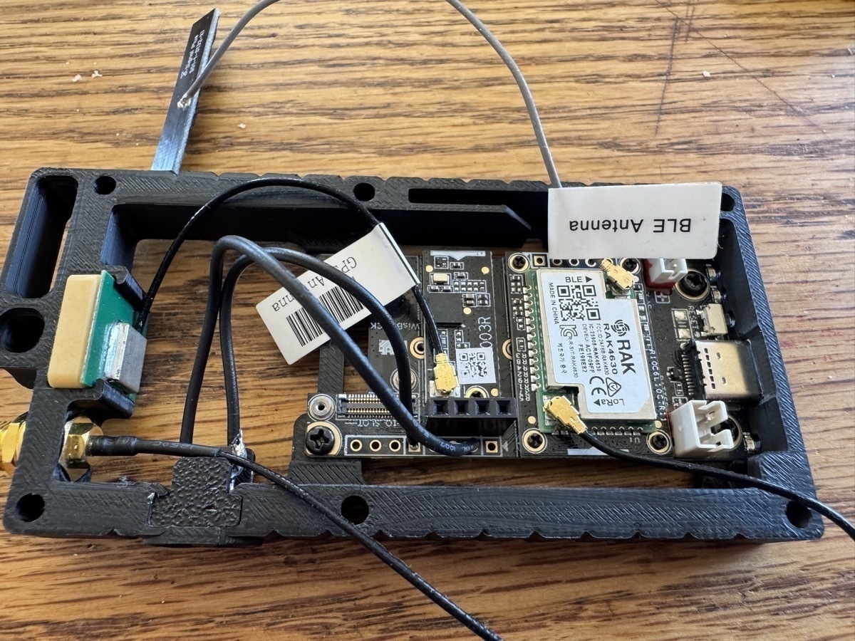 A RAK4631 Meshtastic radio board installed in a black plastic tray that's about to be fitted into a case. There are wires running about.