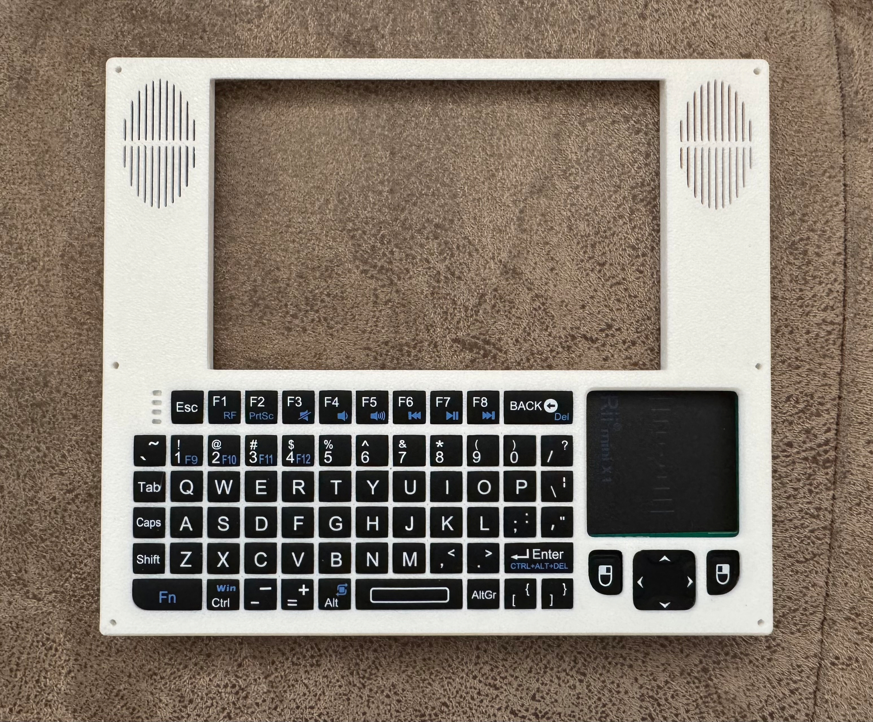 A white plastic laptop front with a tiny keyboard and trackpad mounted in it, ready to attach to the bottom of the case.