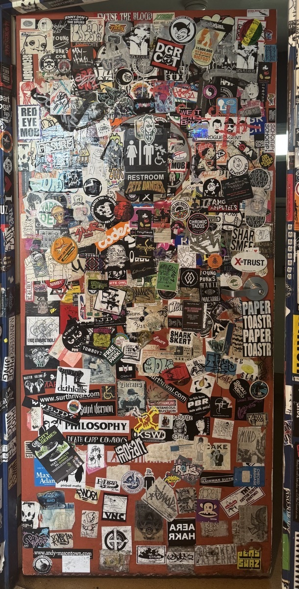 A wood door where nearly every square inch is covered in punky stickers. I regret that I wouldn't even know where to start describing the literally hundreds of stickers.