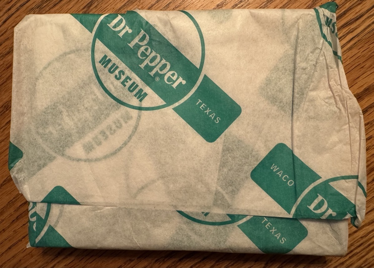 A small, rectangular package wrapped in paper from Dr Pepper Museum, Waco, Texas