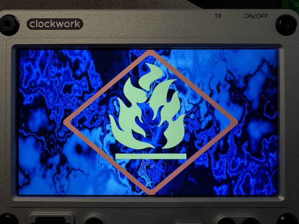 Photo of a uConsole with a Hackers movie-style boot screen with blue plasma flames and a yellow flame logo inside a red trapezoid.