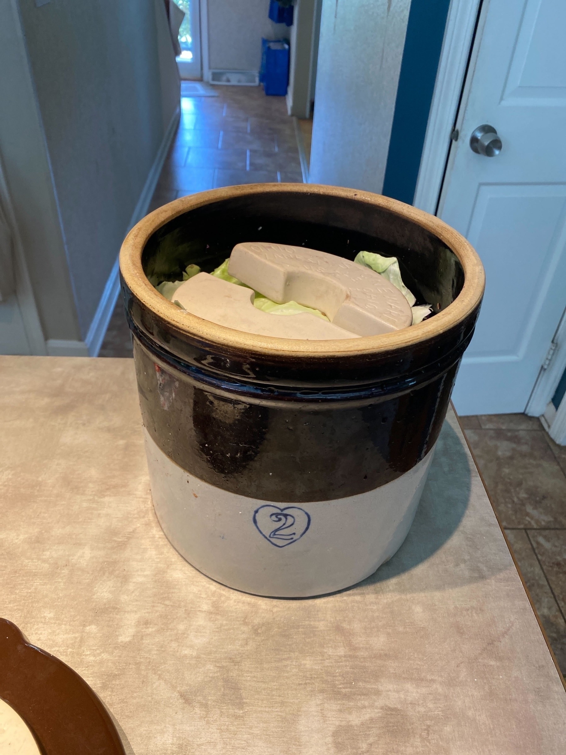 A 2 gallon ceramic crock filled with cabbage 