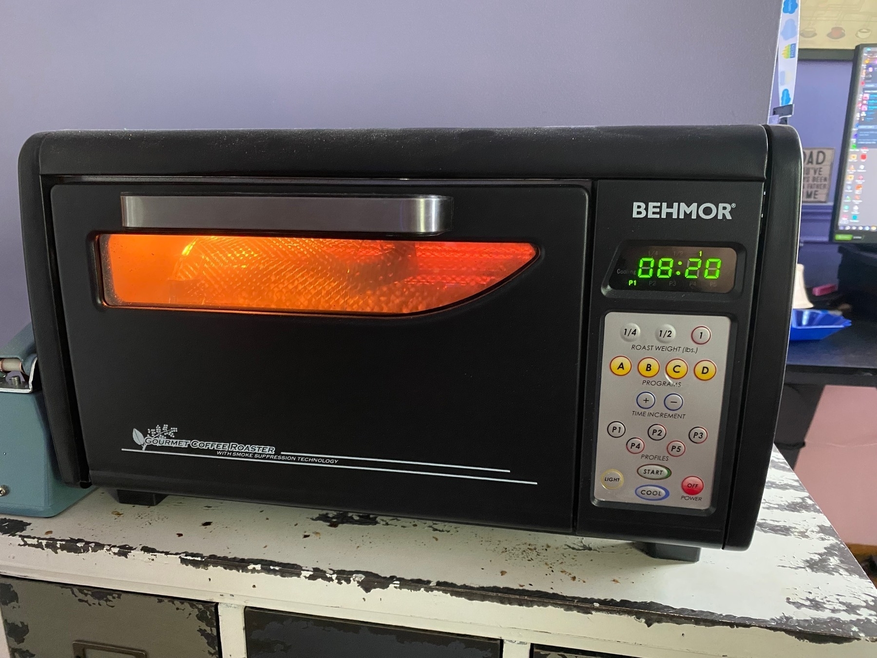 A Behmor drum roaster, glowing deep orange in the drum window where coffee beans slowly turn and roast.