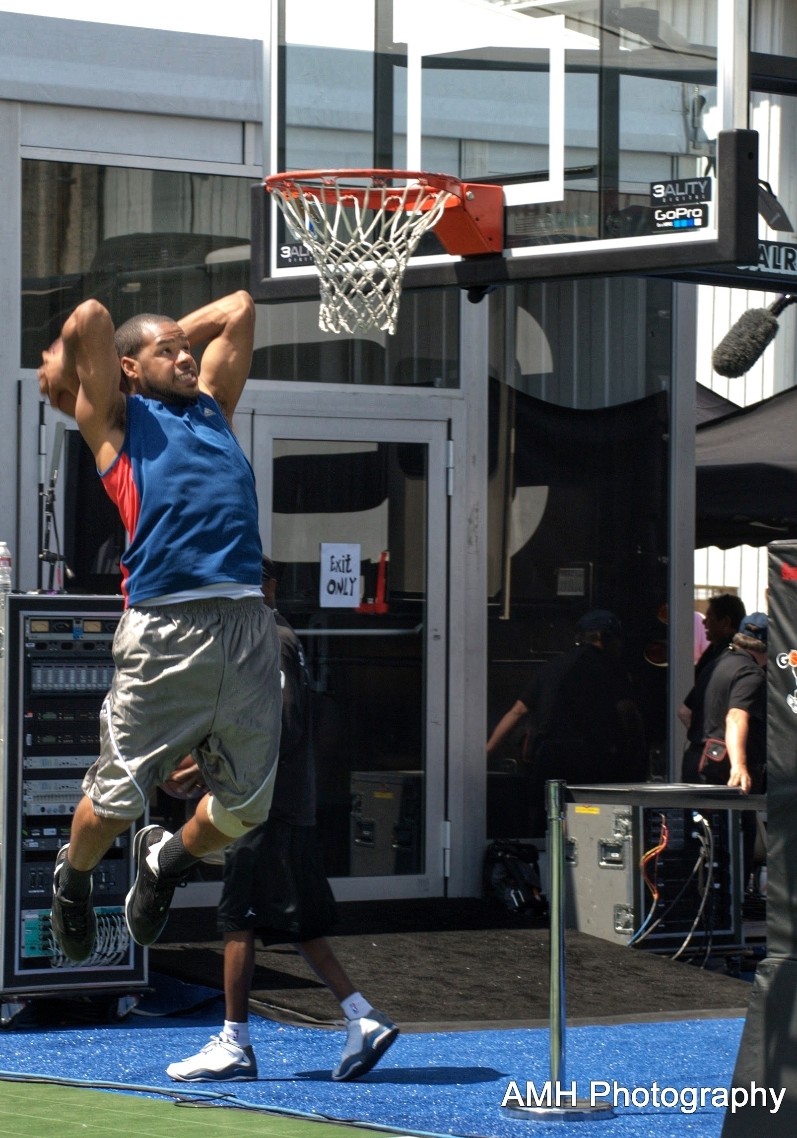 A Black man mid-flight to dunking on a basketball ball court. 