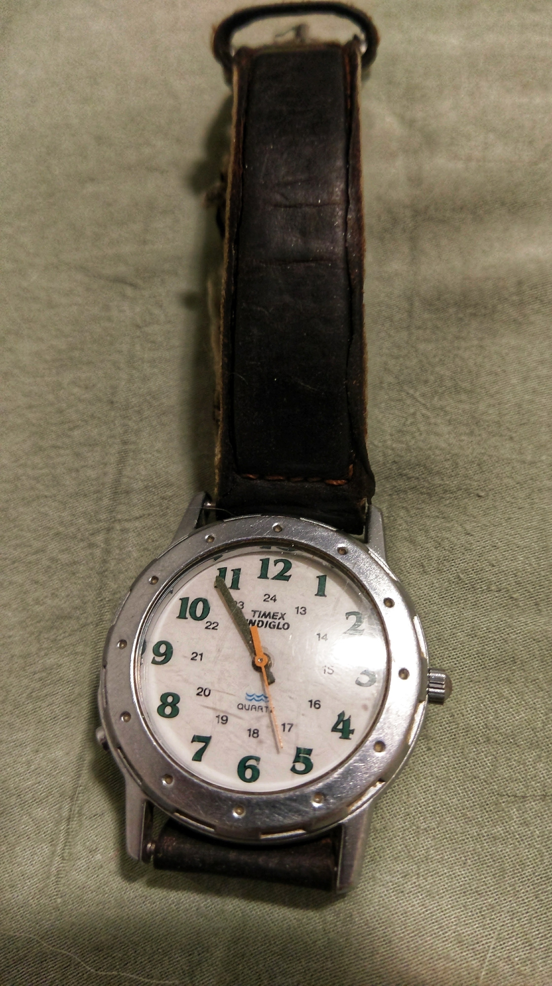An analog Timex indiglo watch with leather wristband. 