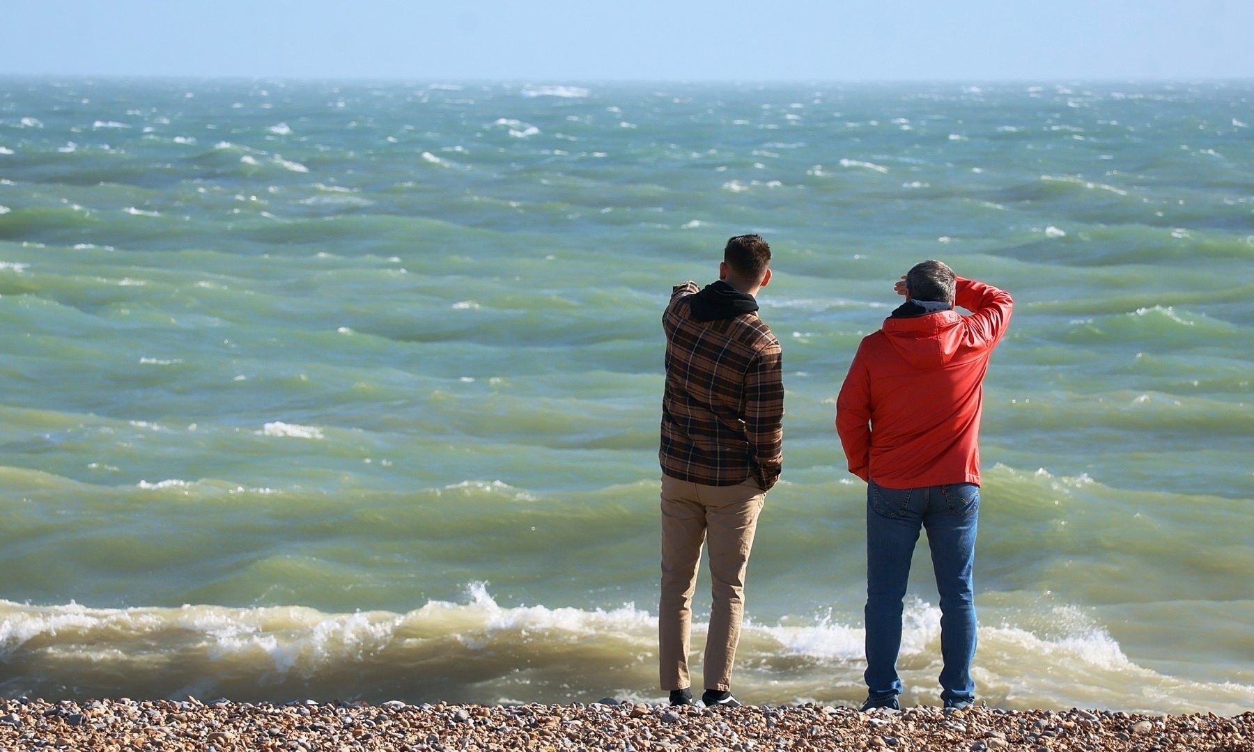 two men standing by the sea on Shoreham Beach. 