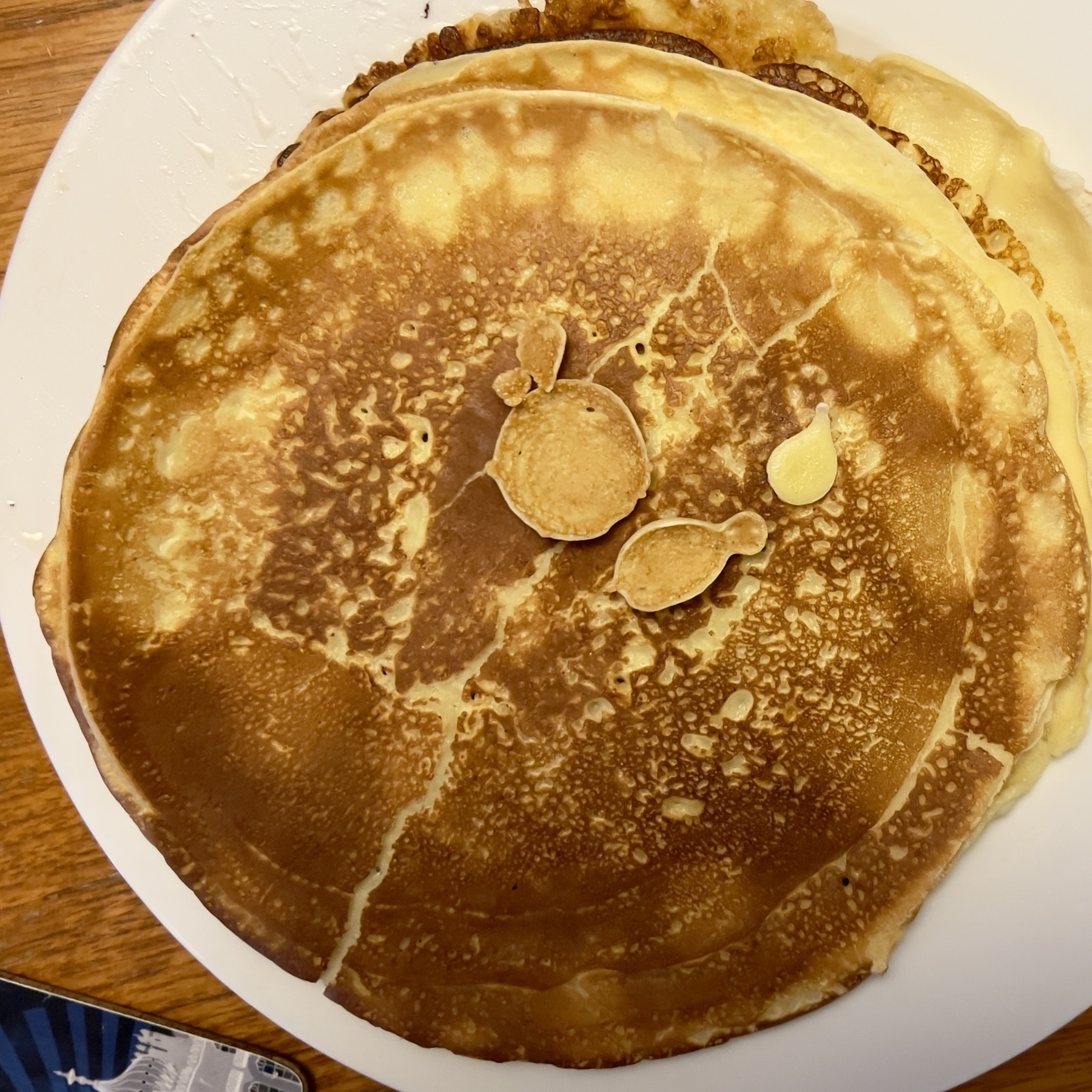 A plate of pancakes with an unusual pattern resembling a face formed on the top surface.