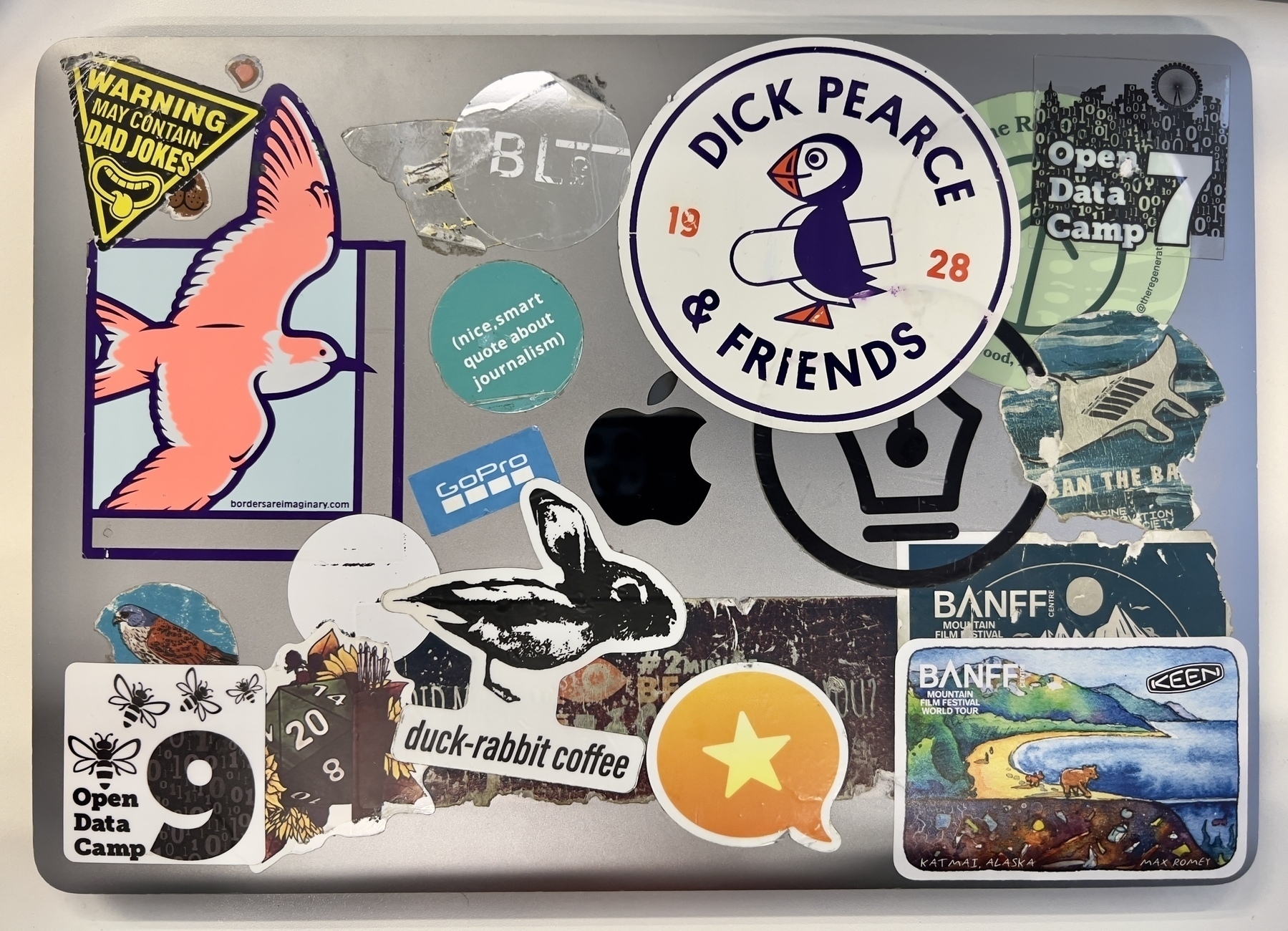 A laptop is decorated with various colorful stickers, including logos, designs, and images from events and brands.