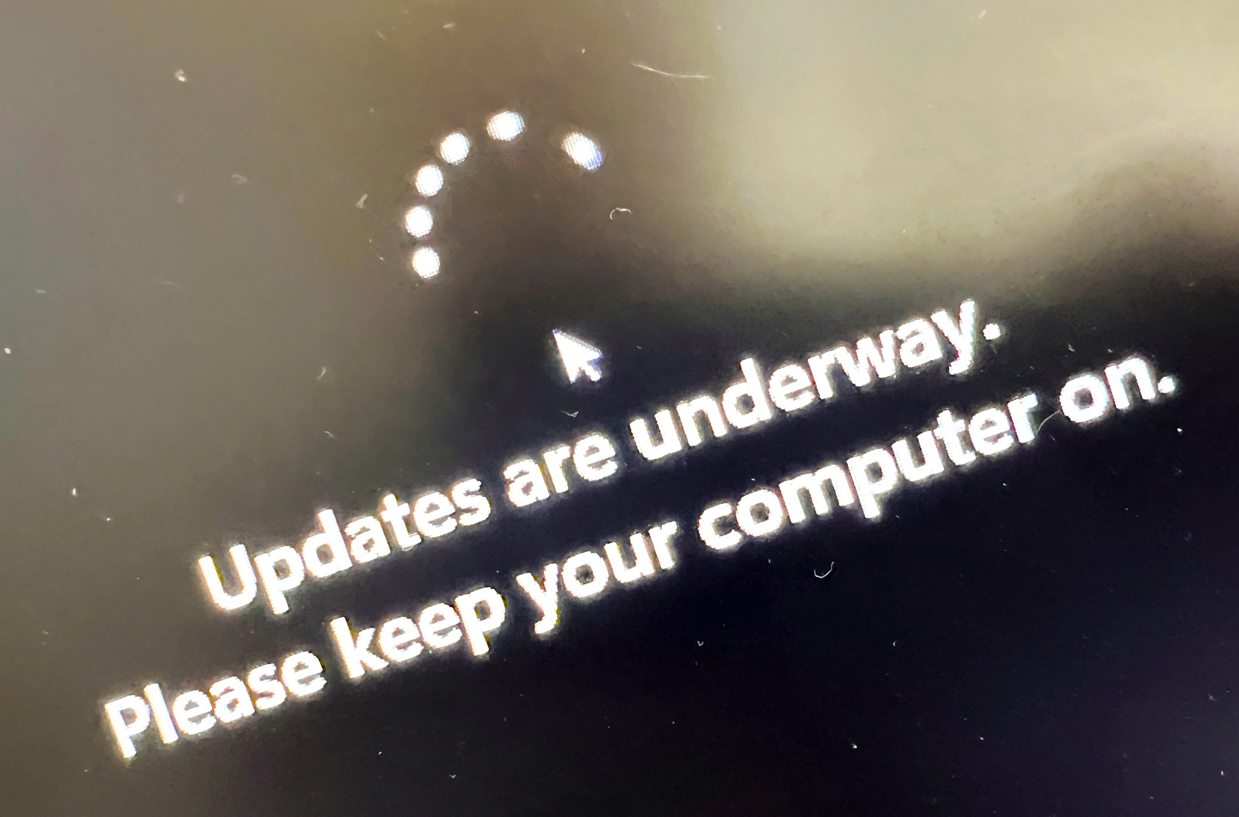 A computer screen displays a message indicating that updates are underway and instructs to keep the computer on.
