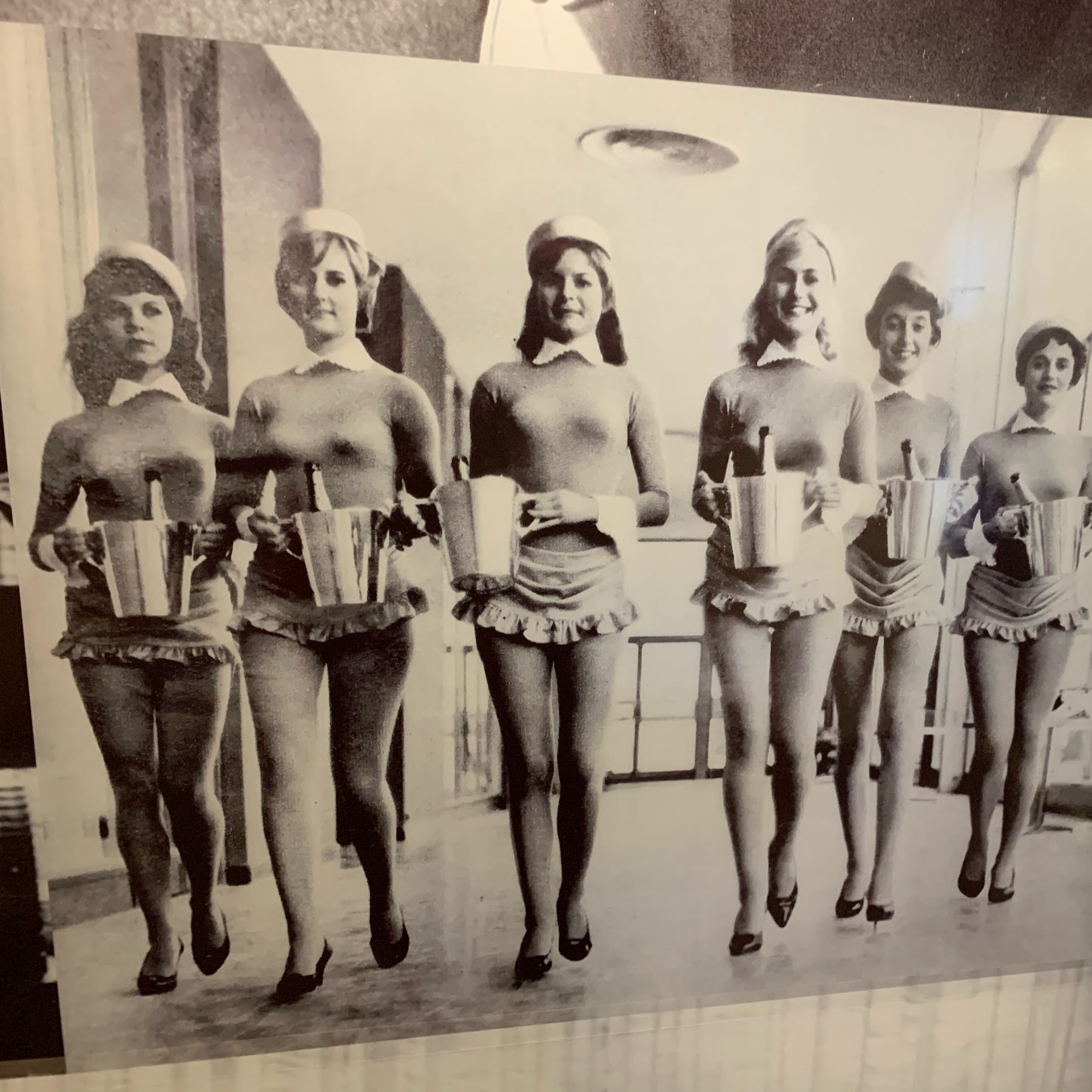 A photo of staff from the Berlin Intercontinental Hotel wearing a catsuit, maid's hats, and a skirt-like thing, all carrying buckets with bottles of champaign