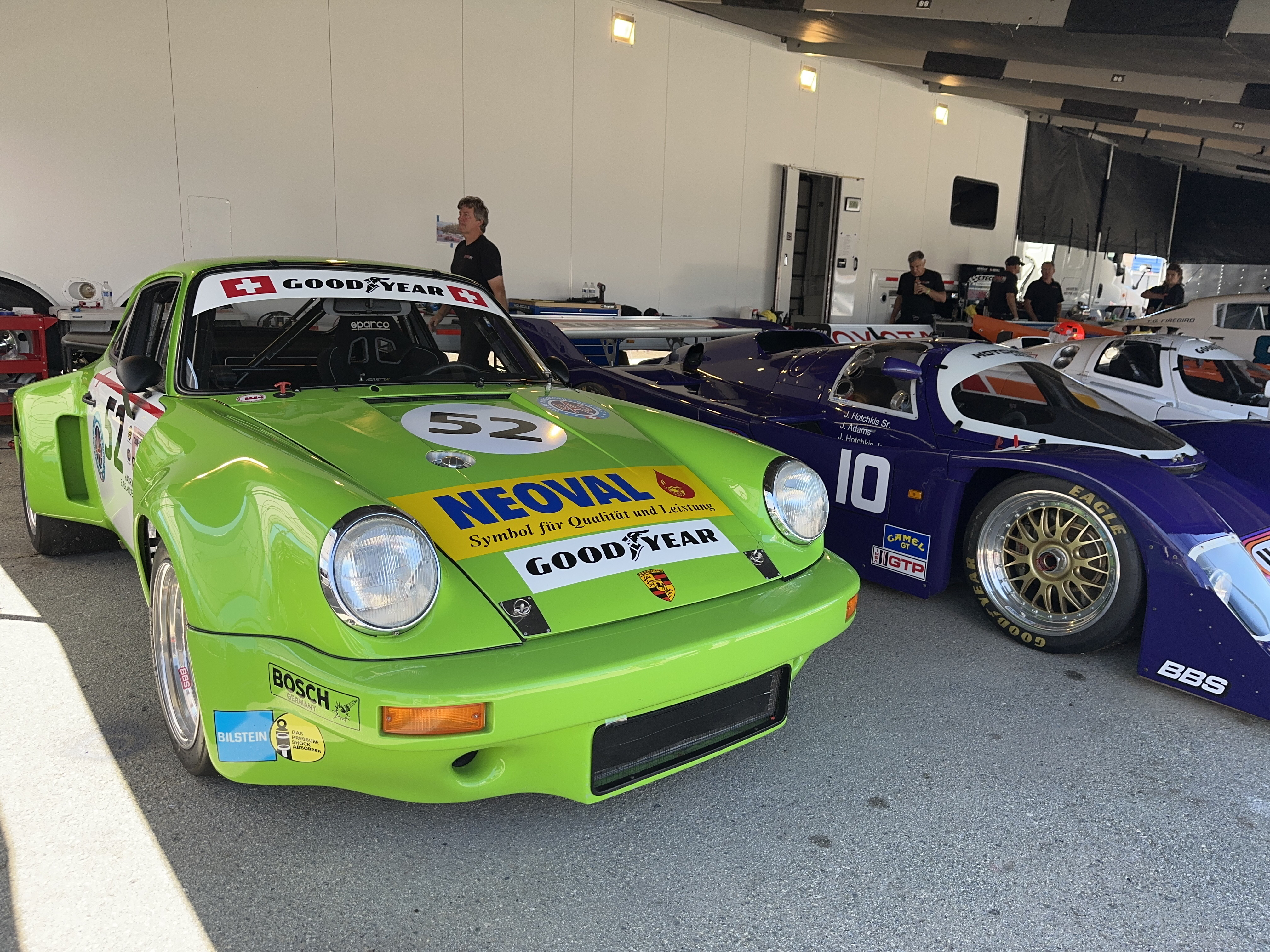 A very green Porsche 911 race car and a 70s era Porsche prototype racecar