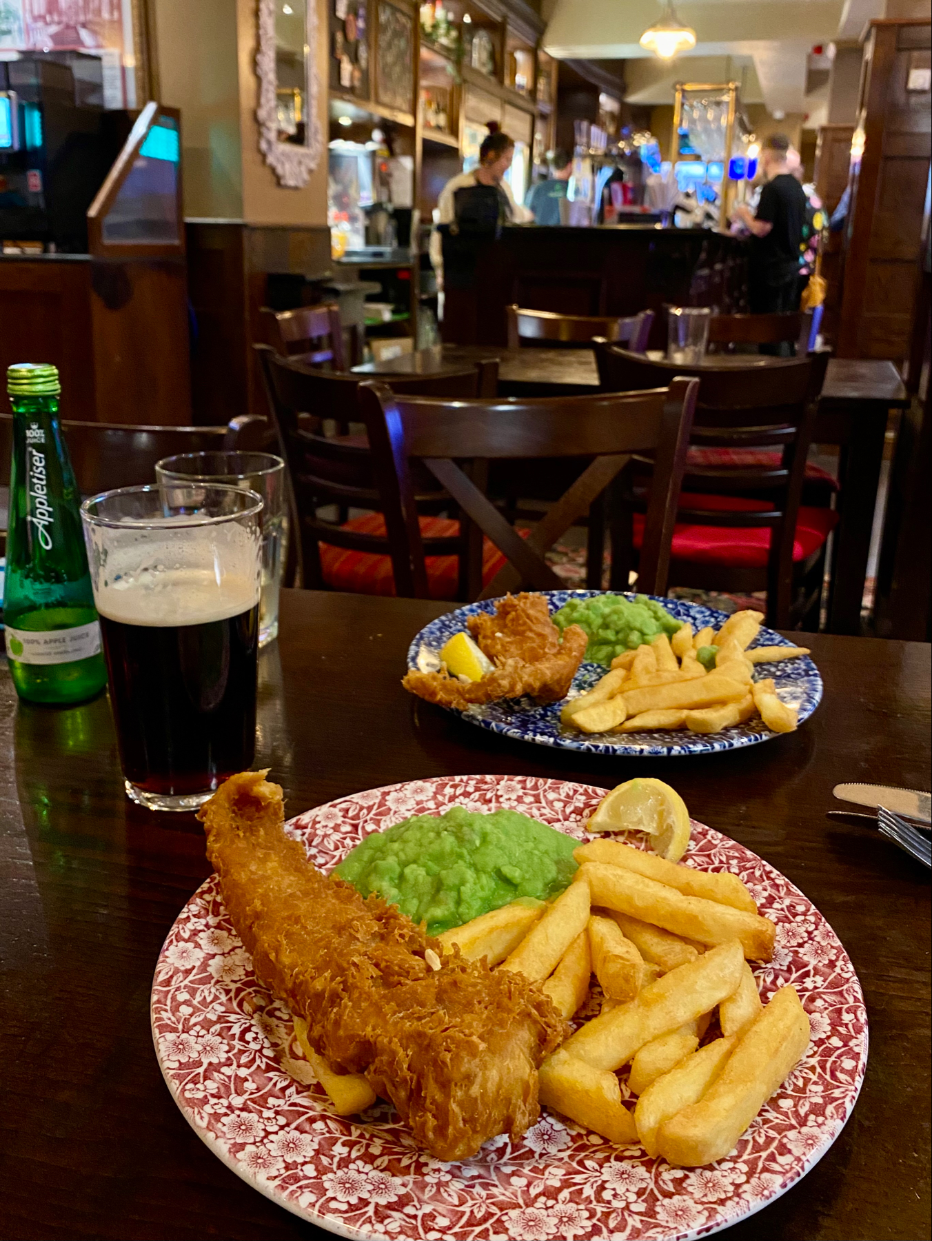 Two plates of fish and chips on a table in a pub