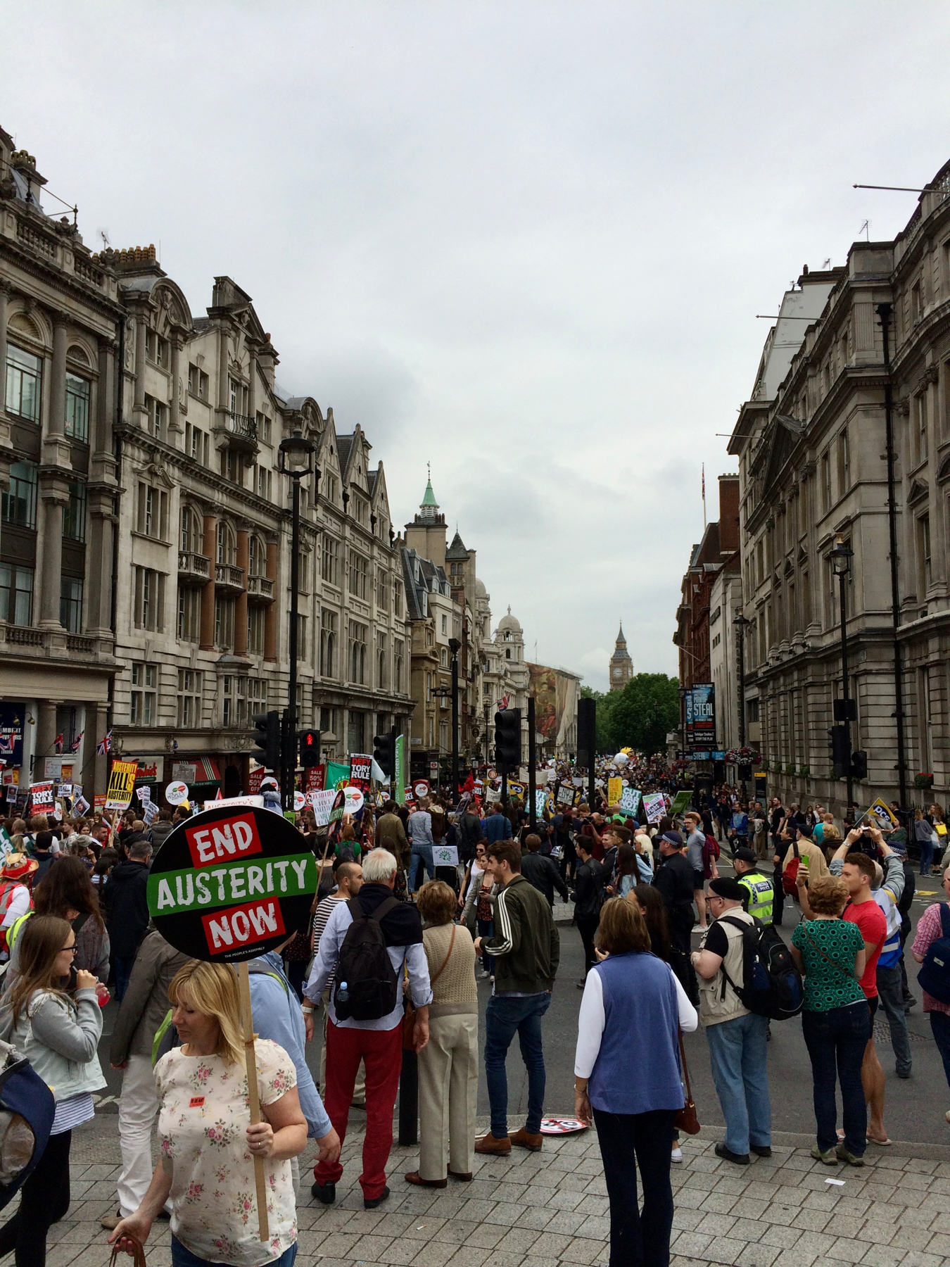 Crowd of people, many holding banners, marching down a city street. Clock tower of Big Ben in the distance.