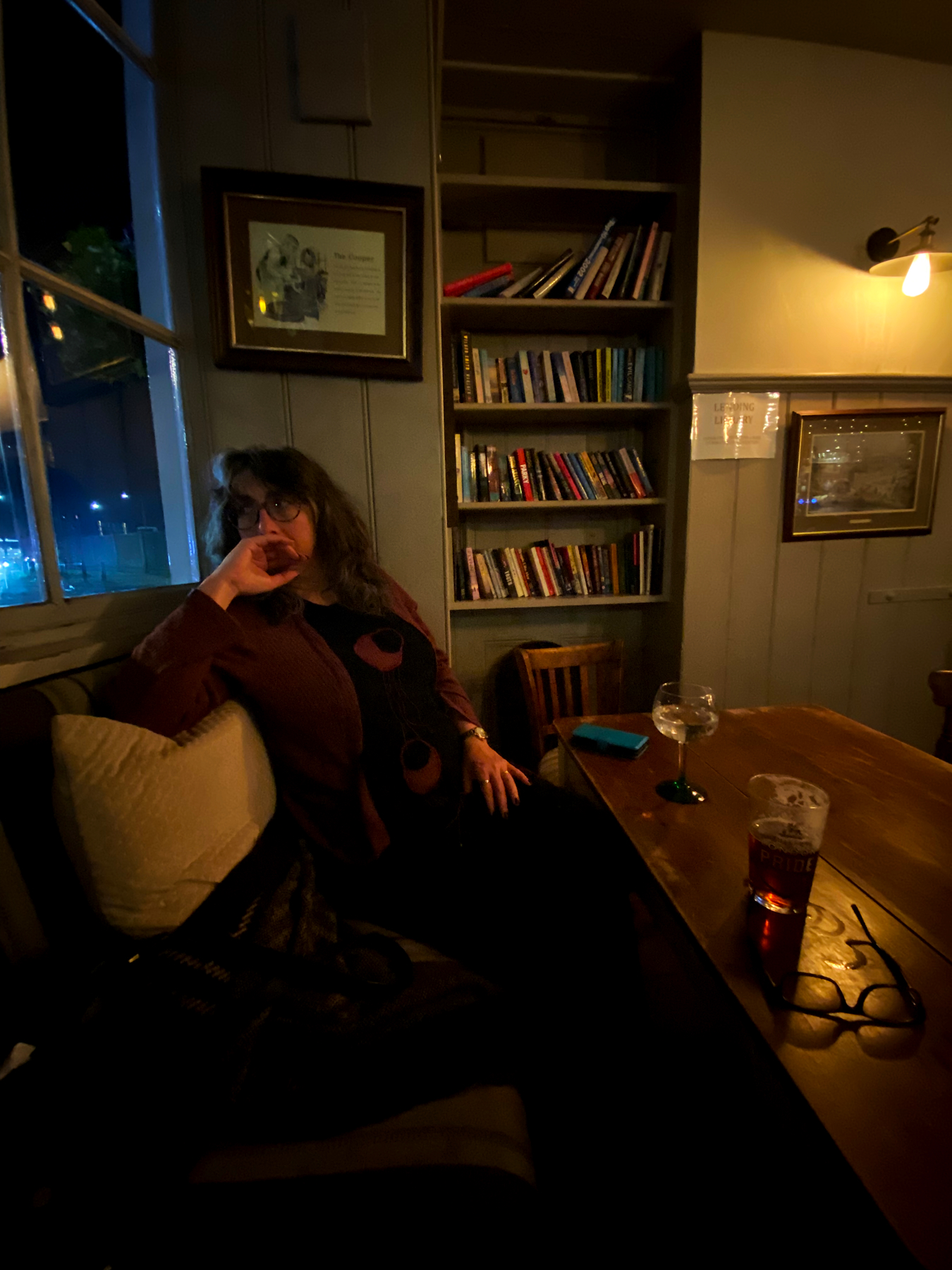 Drinks on a table in a dimly lit pub, bookshelves in the background