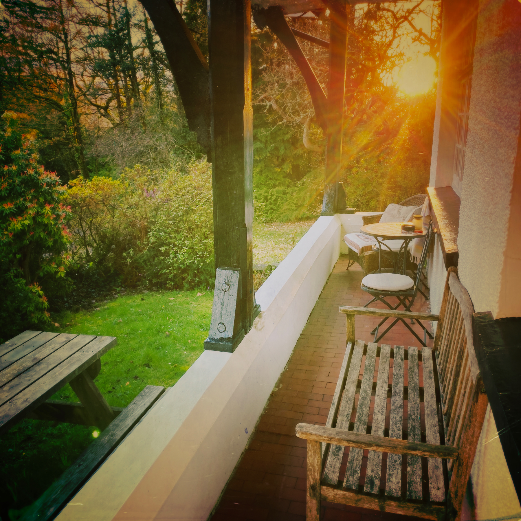 Evening sun shining across a small balcony with bench and table