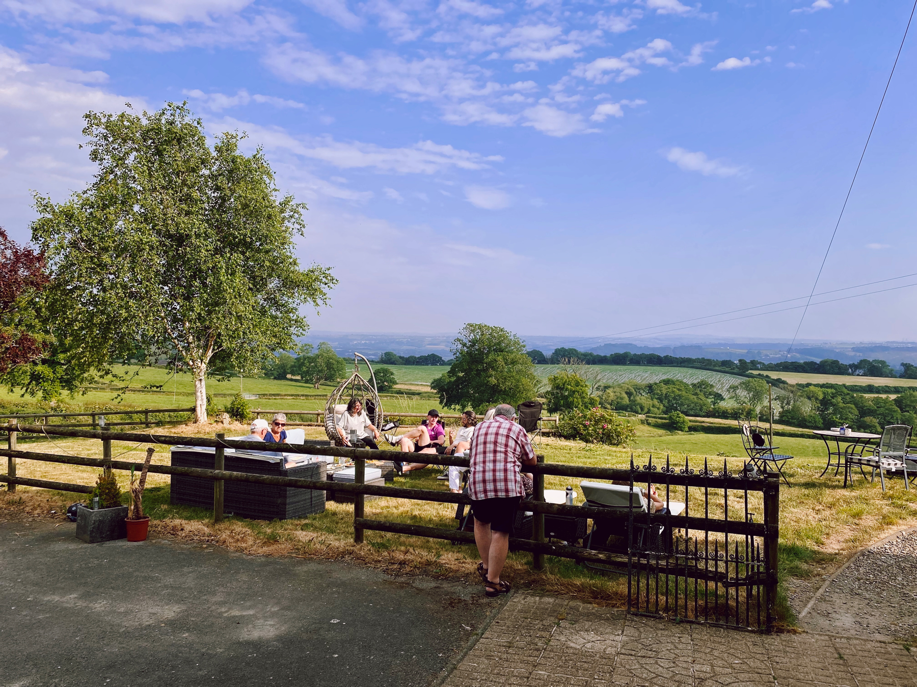 Group of people drinking in foreground, background of fields and blue skies