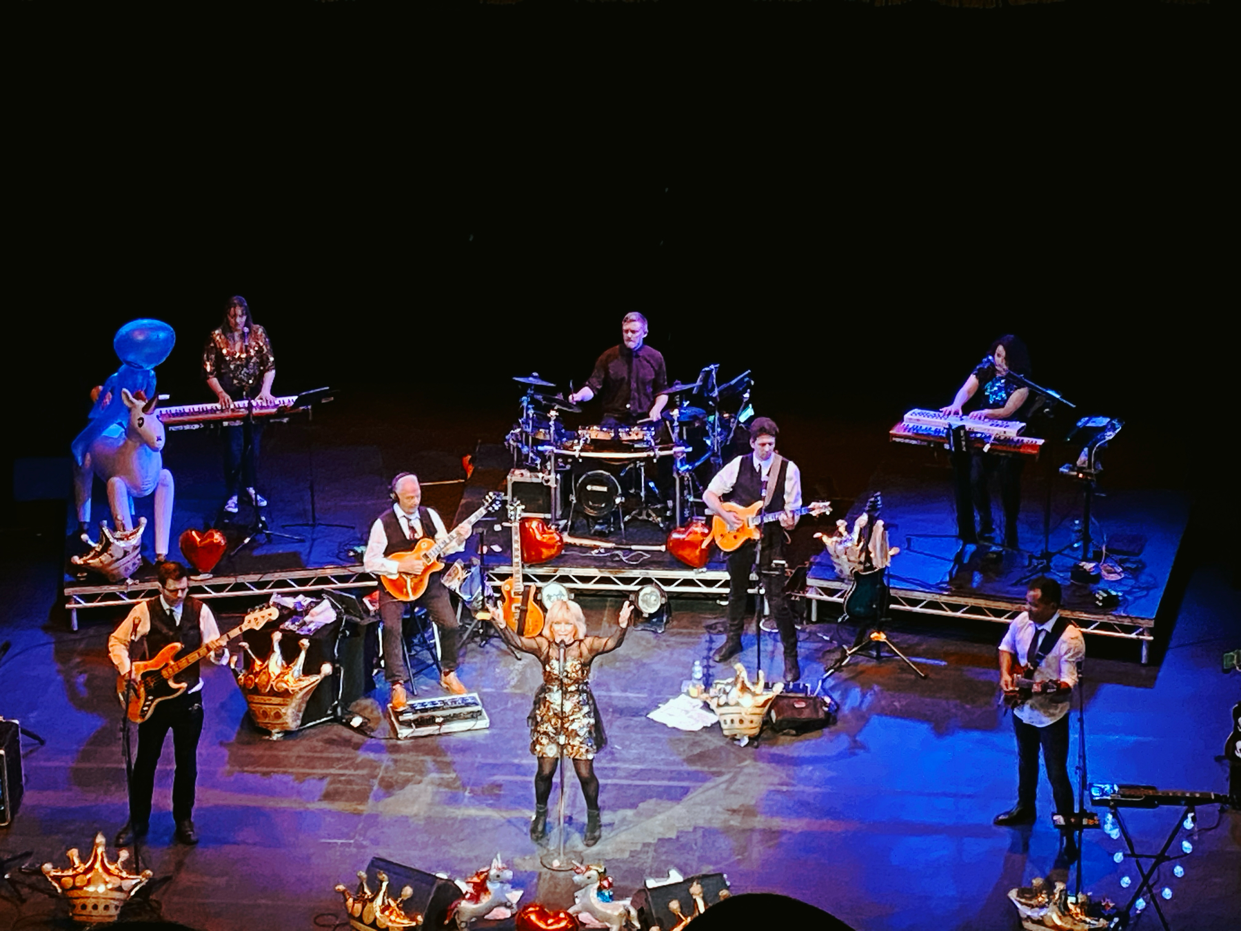 Theatre stage with band of 8 musicians - woman singing in sparkling dress, 4 guitarists, 2 keyboard players and drummer