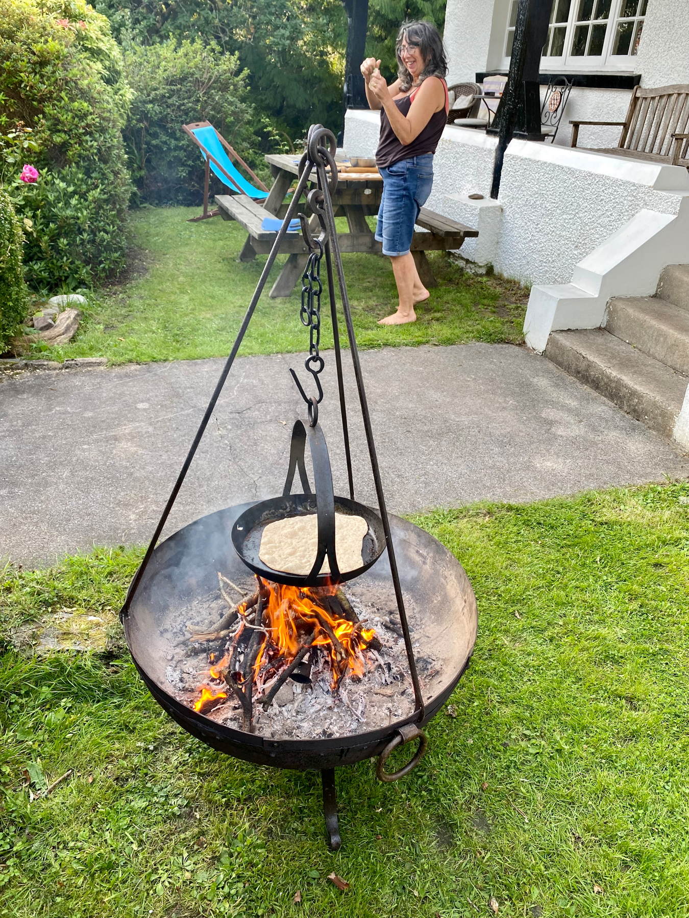 Fire pit with tripod and suspended skillet. Flatbread on skillet