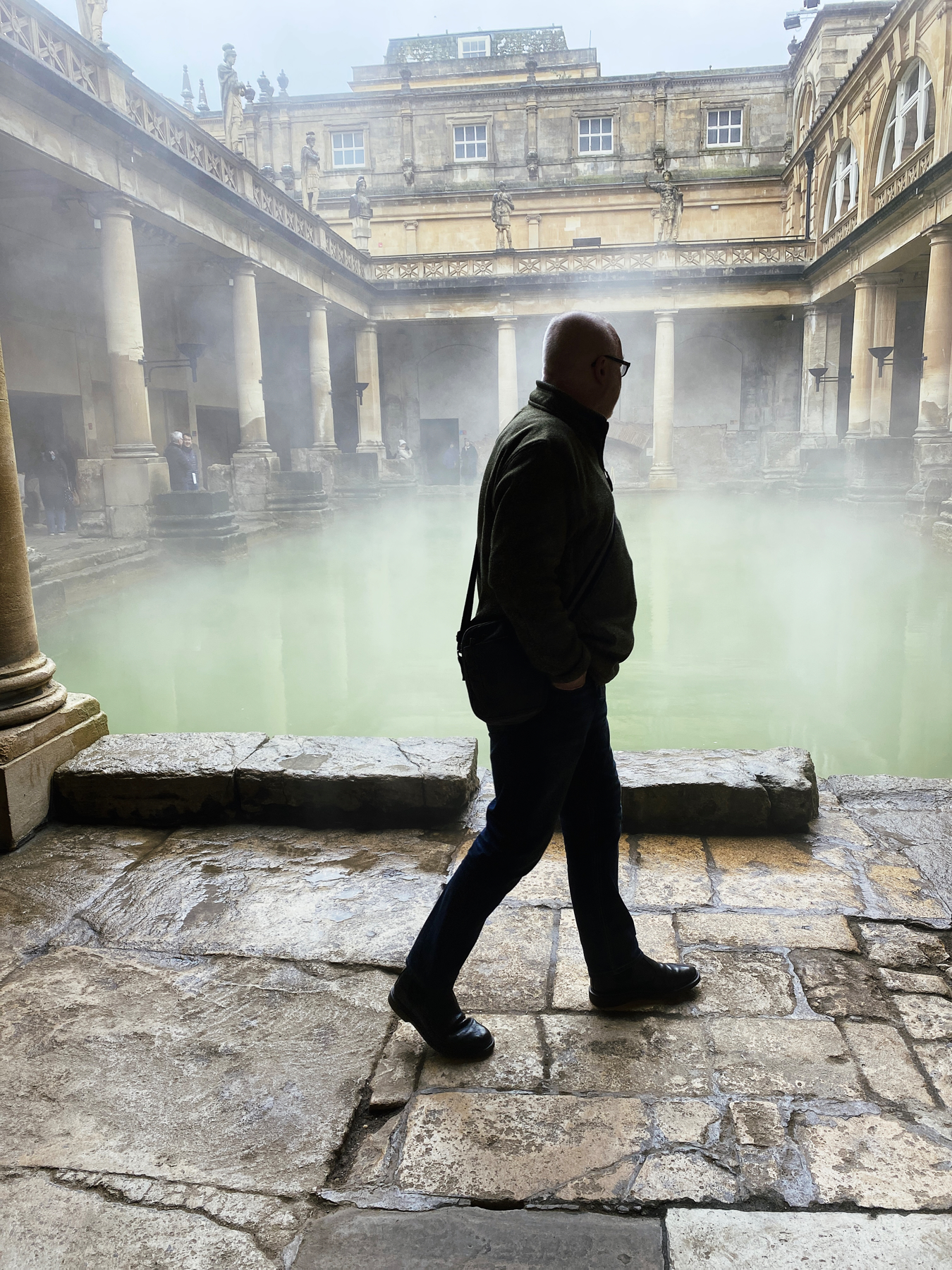Man silhouetted walking in front of Roman Bath