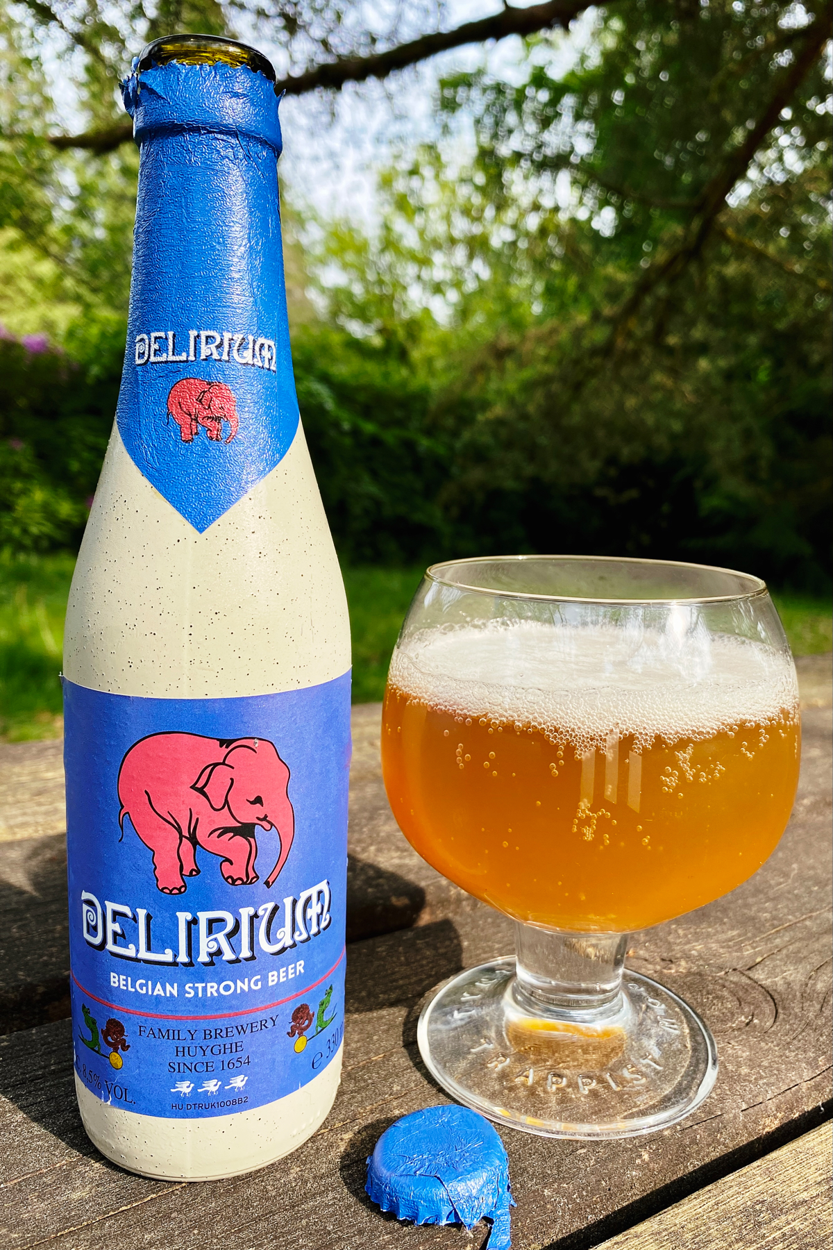 Colourful bottle with pink elephant on label next to a glass of pale golden beer