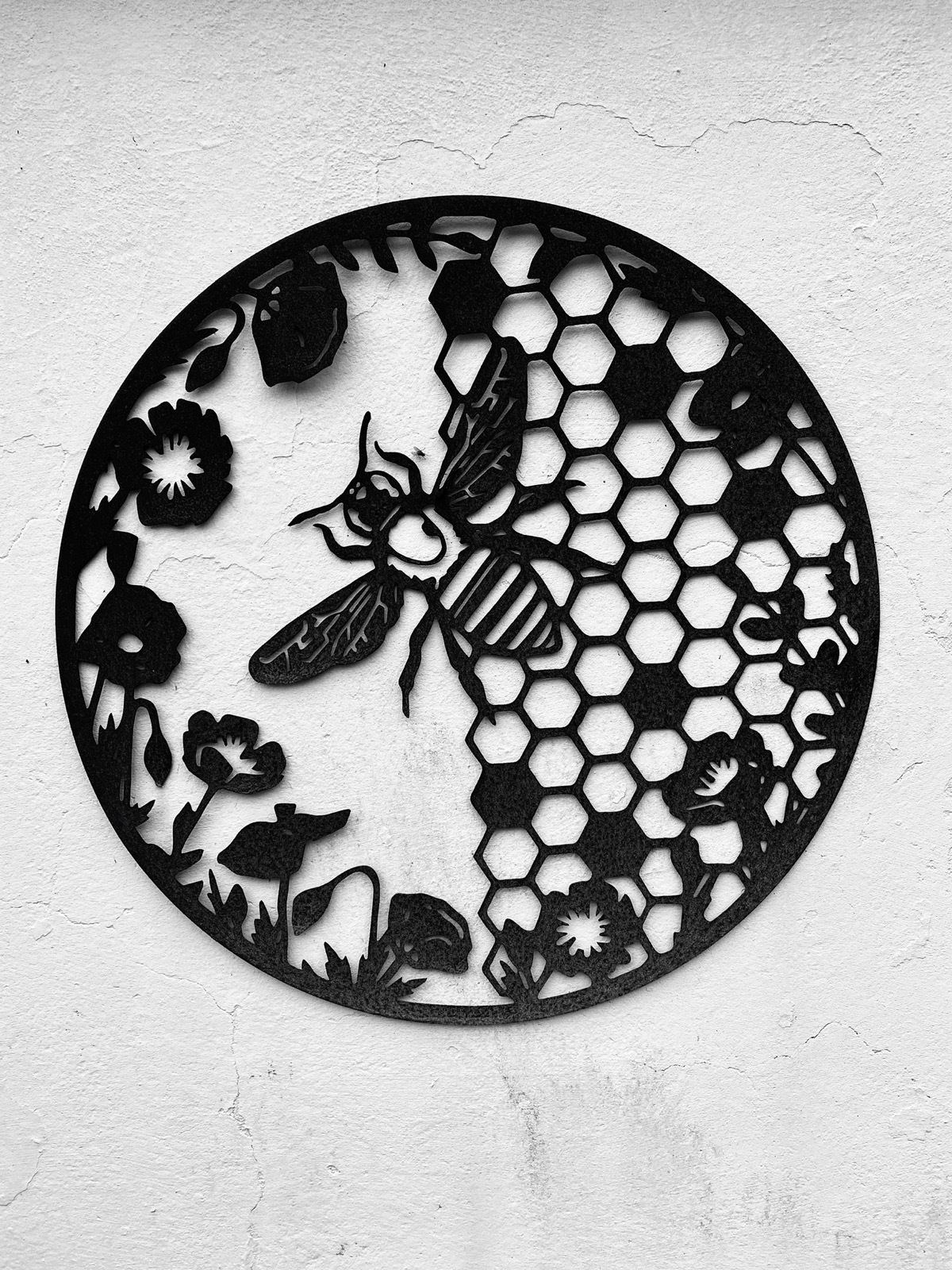Monochrome image of metal plaque of a bee, honeycomb and flowers