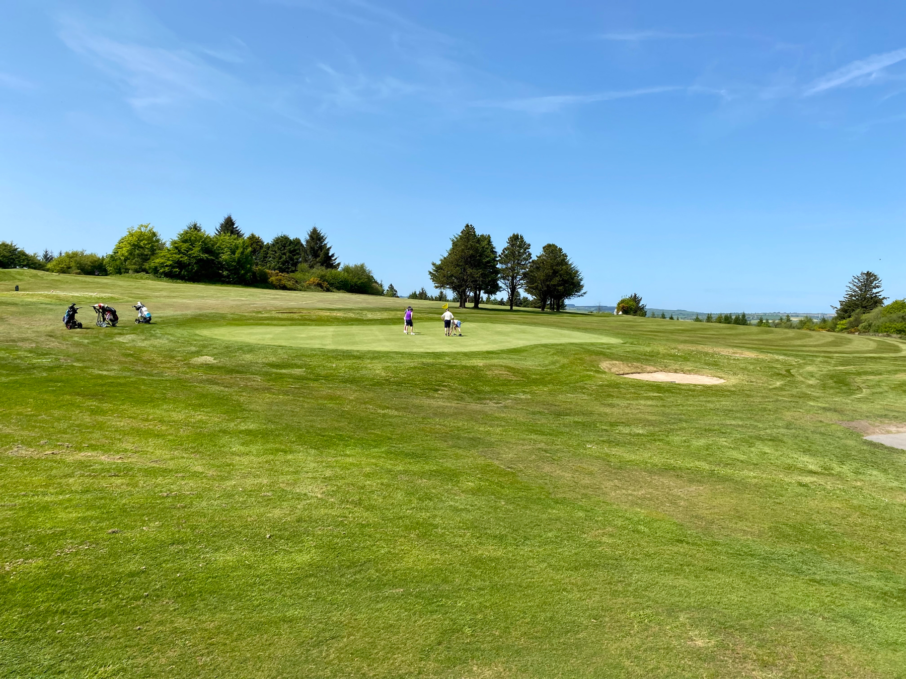 View over a golf course and green, blue skies above.