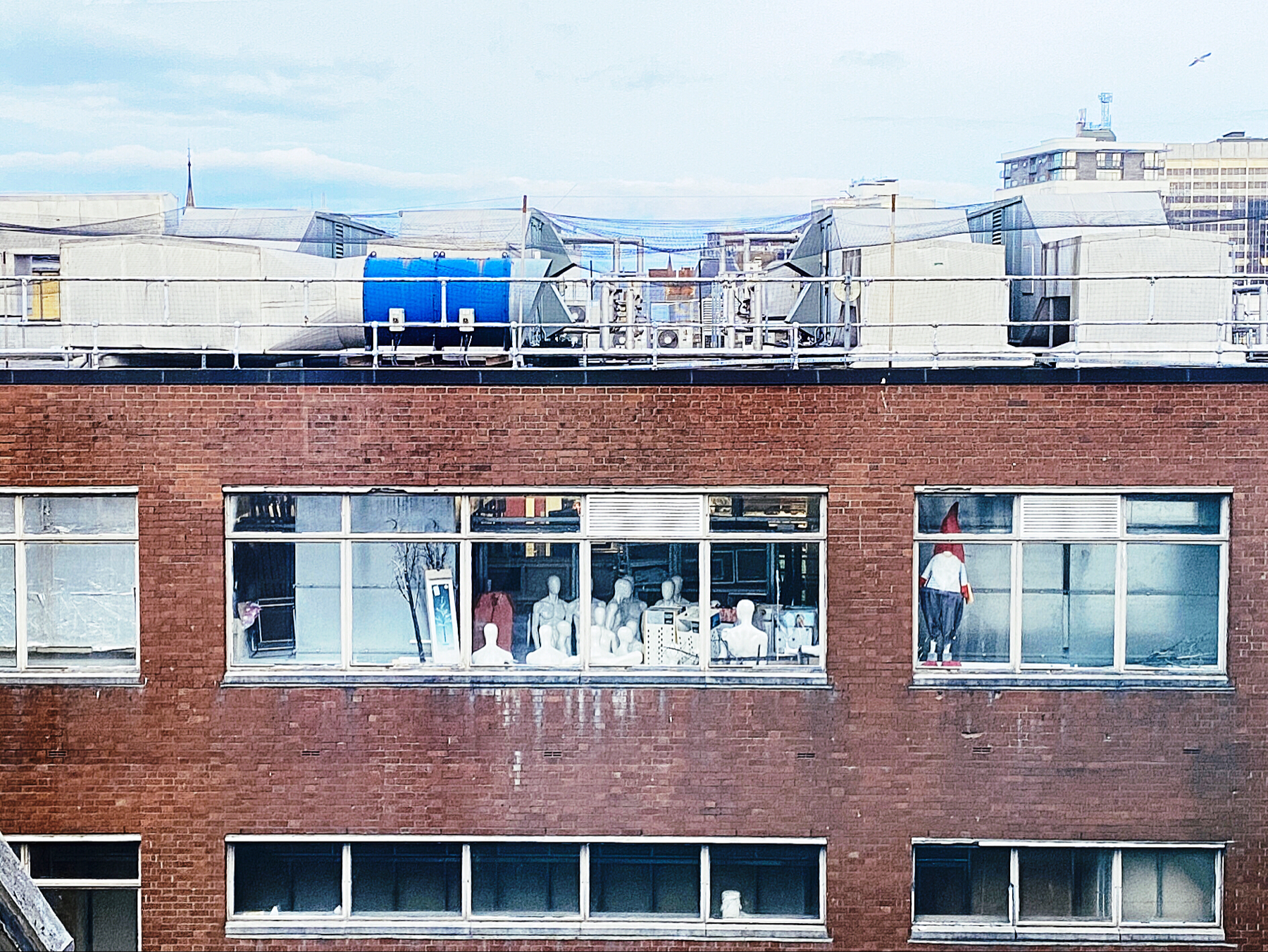 View into an office building window behind which is a group of mannequins