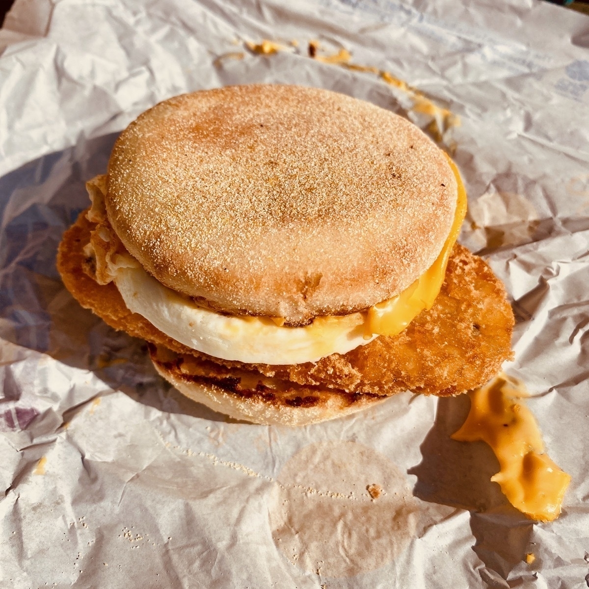 Close up of fried egg, cheese and hash brown in a muffin