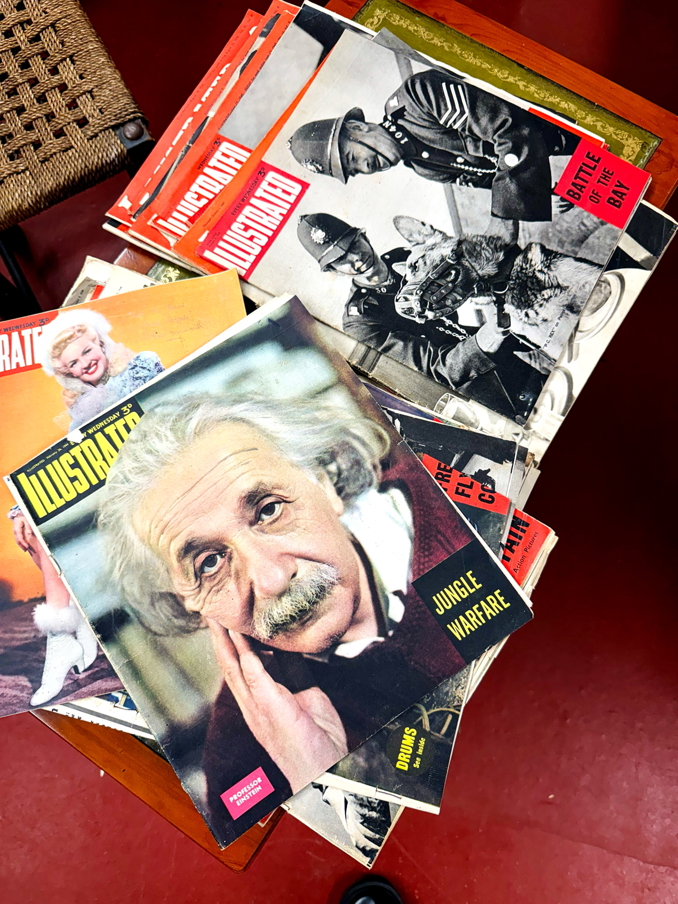 Auto-generated description: A collection of vintage magazines, including one featuring Albert Einstein on the cover, is sprawled across a wooden table.