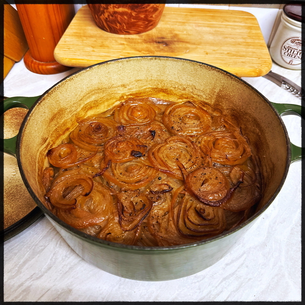 A green pot contains cooked slices of onions that appear to be caramelized.