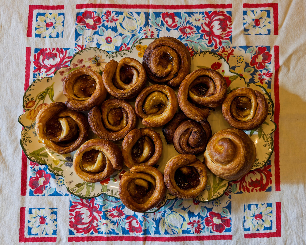 A platter of spiral pastries is displayed on a colorful floral-patterned tablecloth.