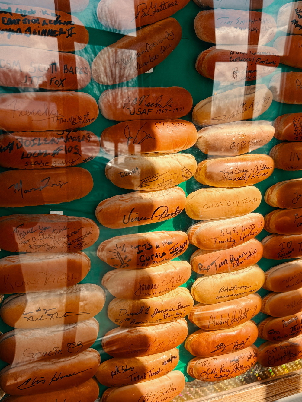 A display case containing numerous baseballs, each signed with various autographs and arranged in rows.