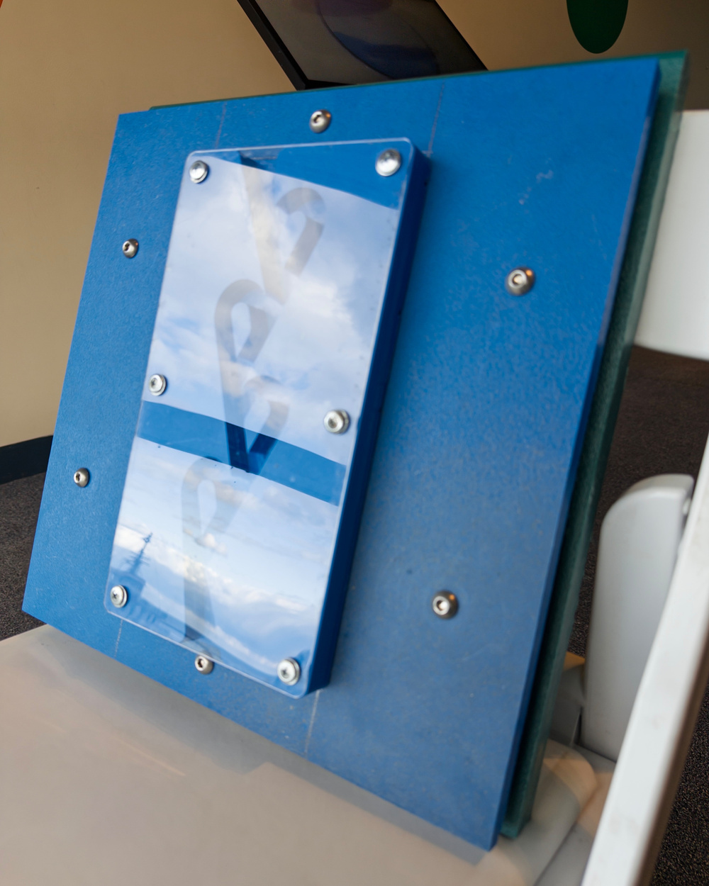 A blue device with a mirrored surface is mounted on a stand.