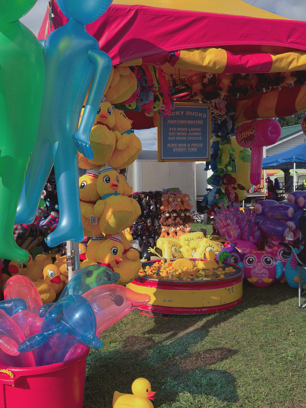 A colorful carnival stall is filled with inflatable toys, stuffed animals, and various games.