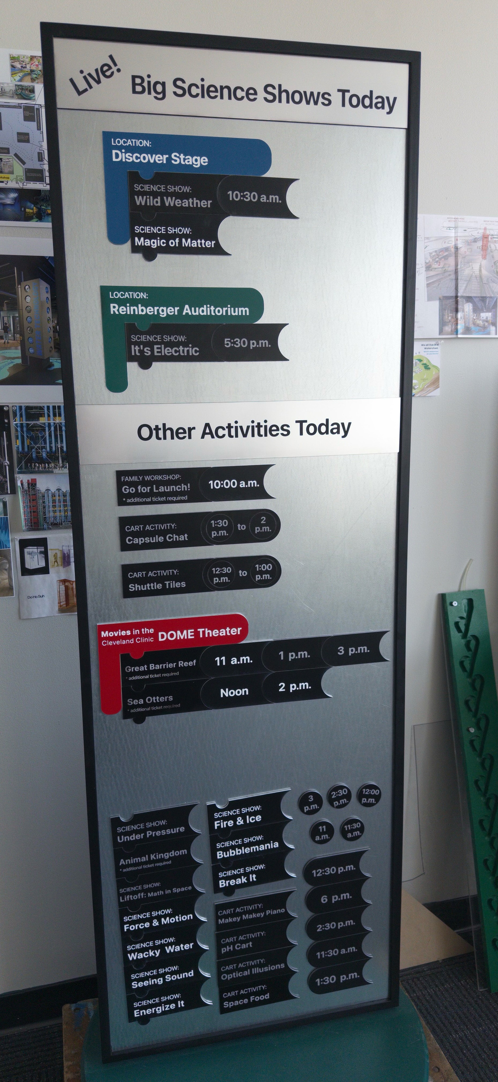 A schedule board lists times and locations for science shows, activities, and movies occurring today.
