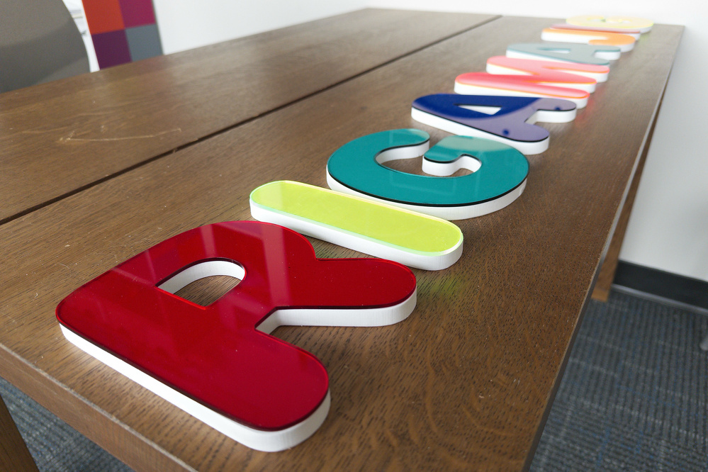 Colorful, three-dimensional letters spelling Play are arranged on a wooden table.