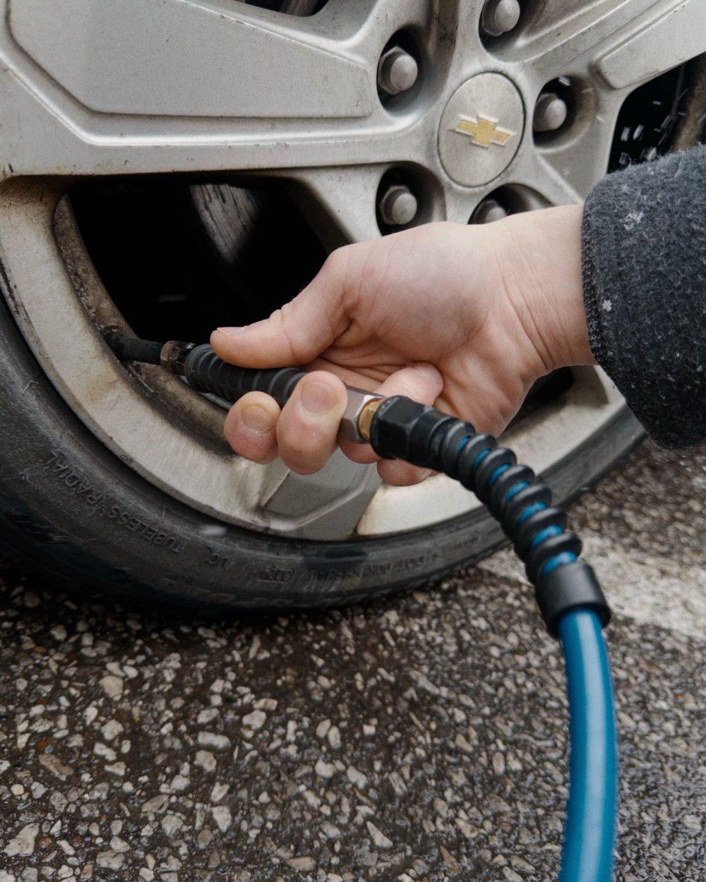 A person is inflating a car tire using an air hose.