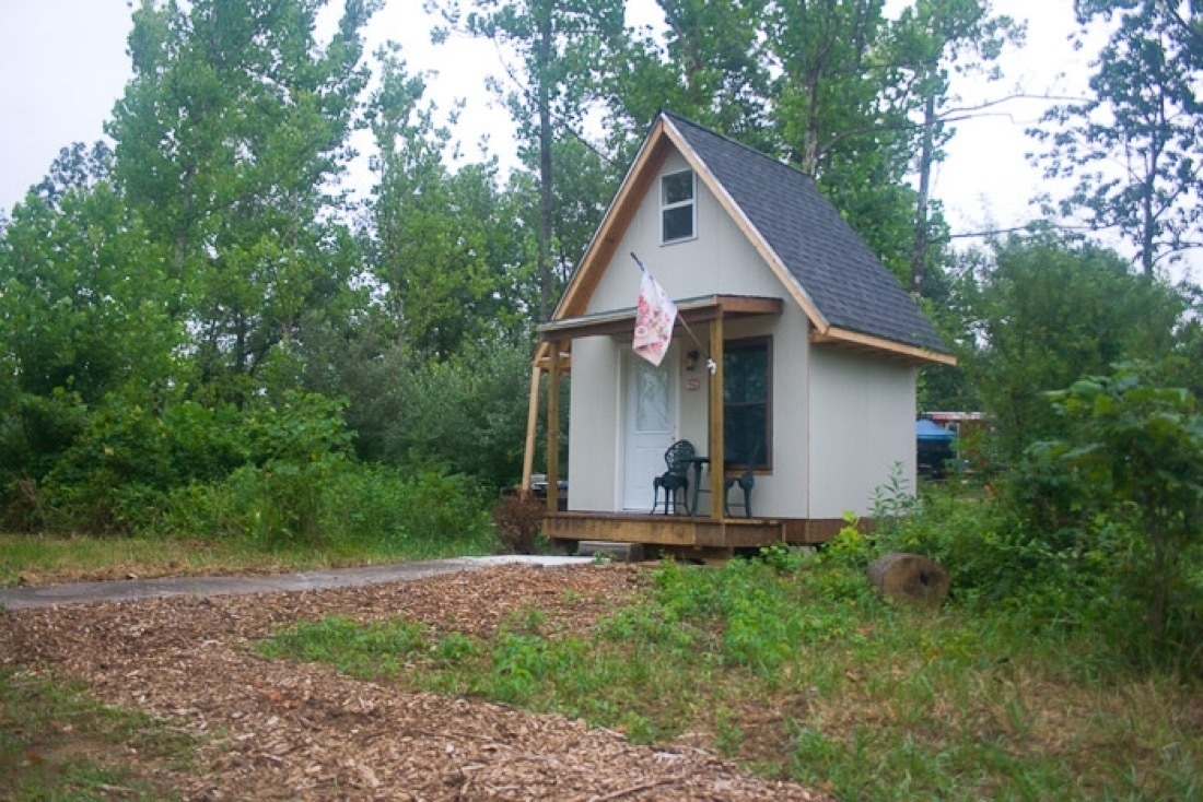 A pale gray tiny house, 2 stories, A-Frame style