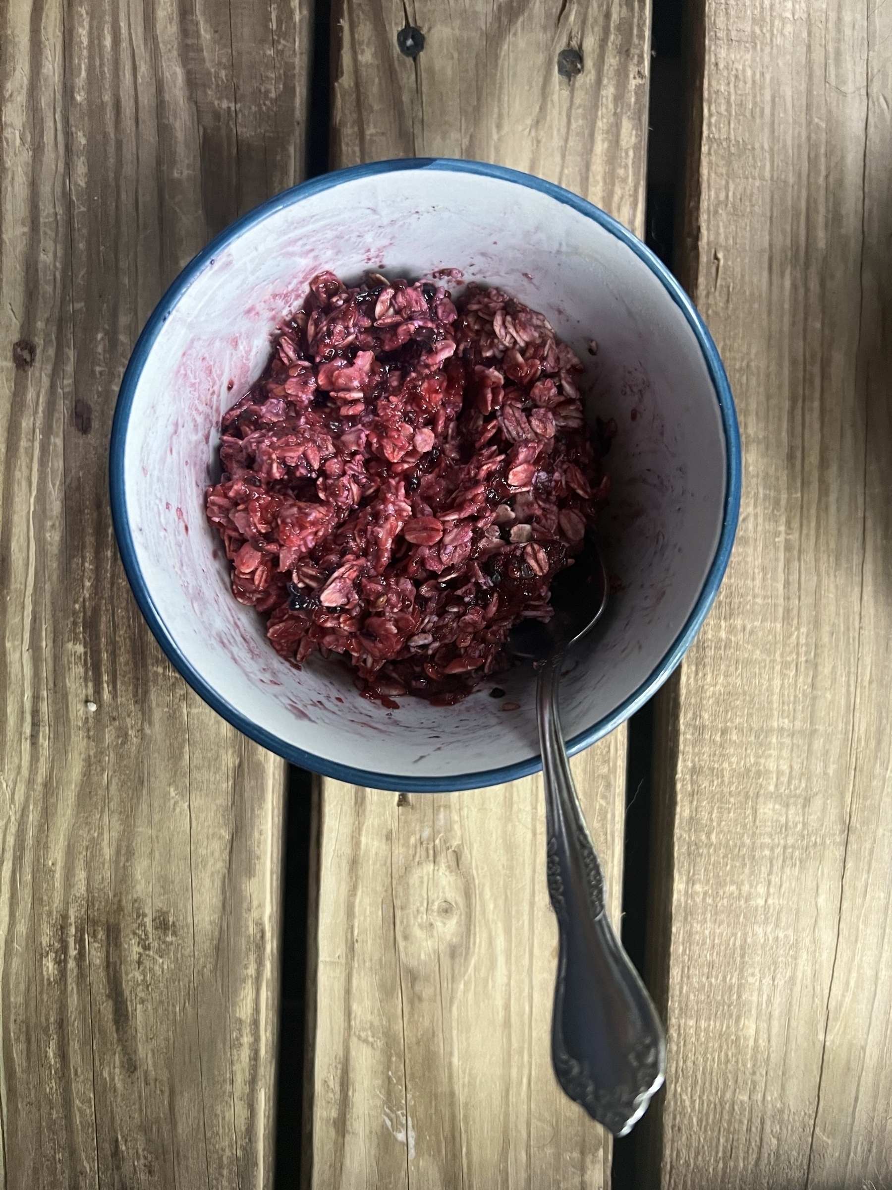 A bowl of cooked oatmeal that has been mixed with blackberries making the oatmeal a pleasant plum colored purple