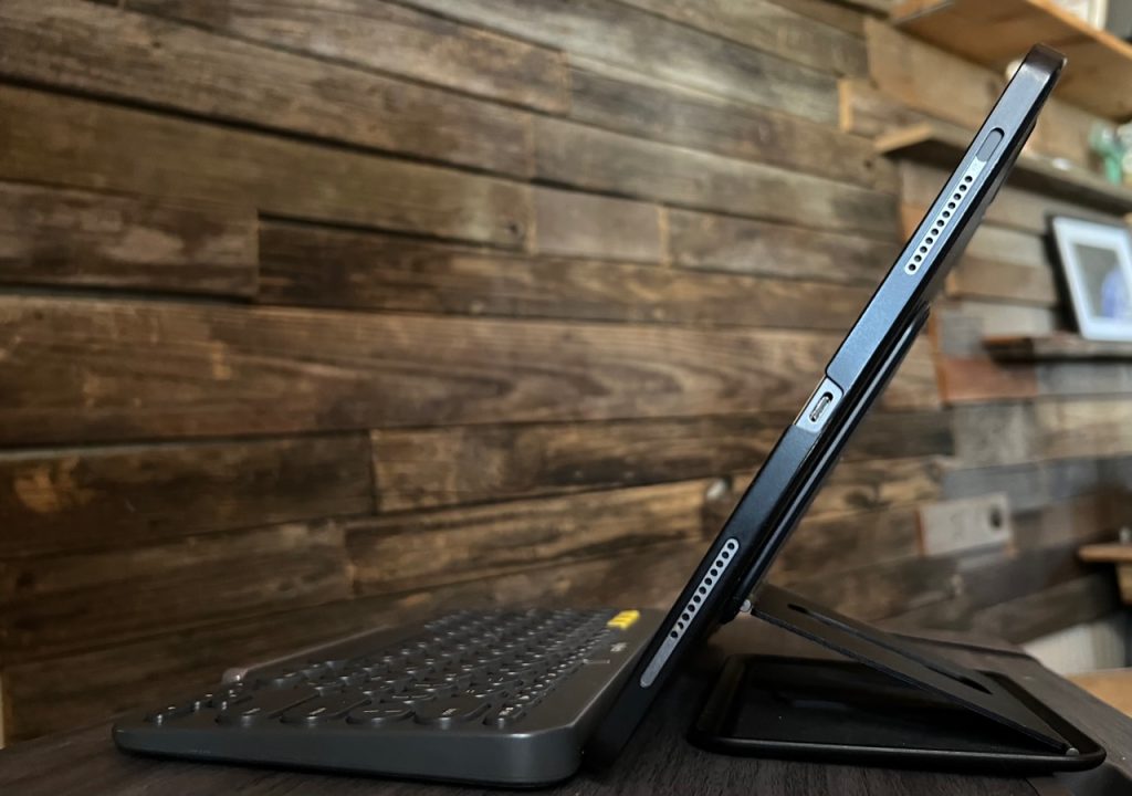 An image of an iPad Pro sitting on a lap desk. The images is from the side showing that the iPad is propped up with a kickstand attached to the back. A keyboard is in front of the iPad.