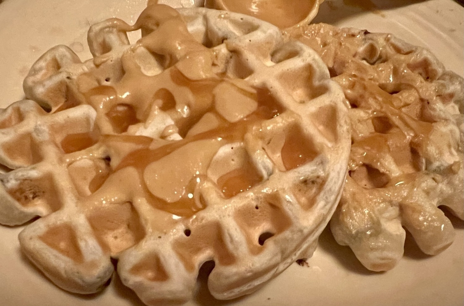 ￼two waffles, on a plate with peanut butter and caramel on top