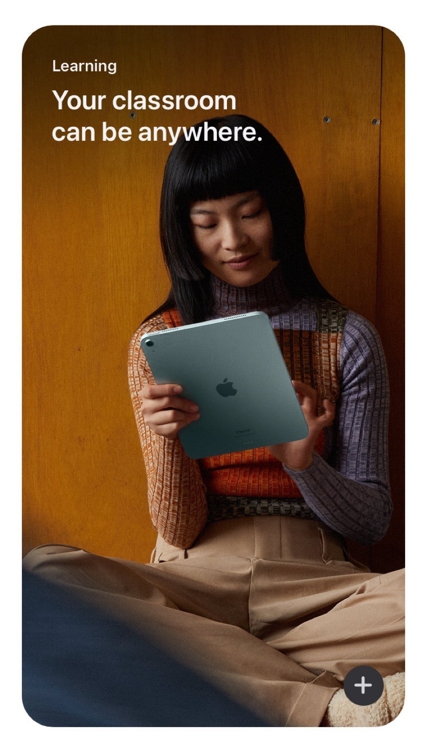 A screenshot from Apple's iPad website. Text reads: Learning Your classroom can be anywhere. There is image of a young woman holding an iPad and sitting crosslegged below the text.